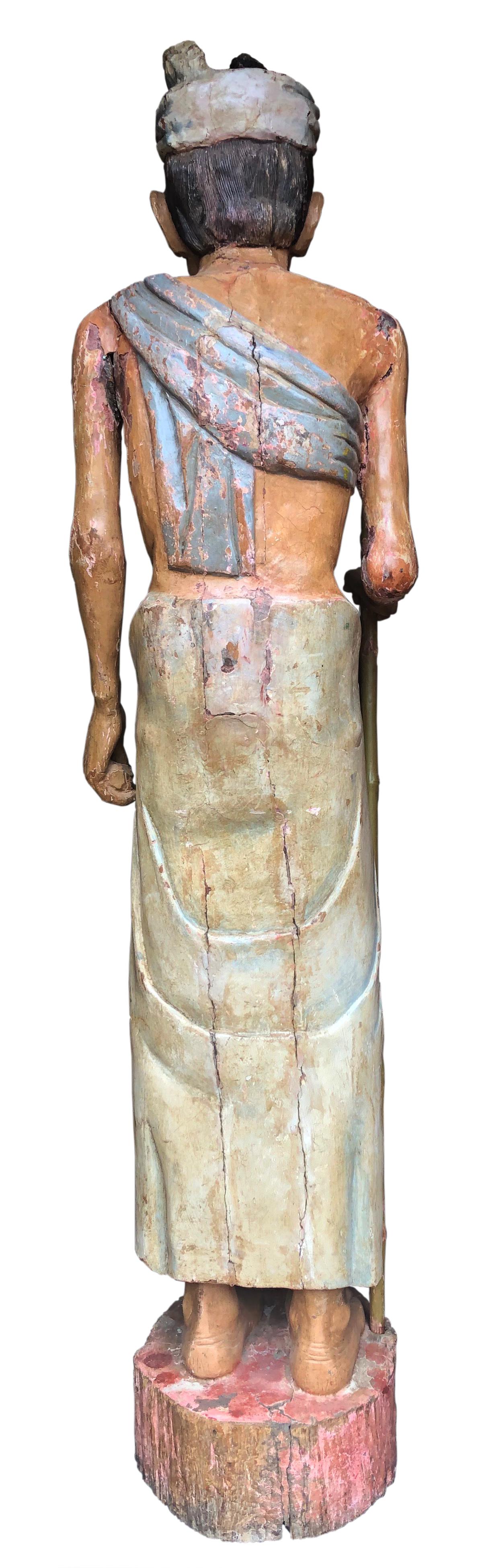 Presumed to date from the late 19th century, this life-sized Folk Art carved and hand painted study depicts a Native man dressed in traditional attire and holding a staff. The artist is unknown and this sculpture is unsigned and done in a very