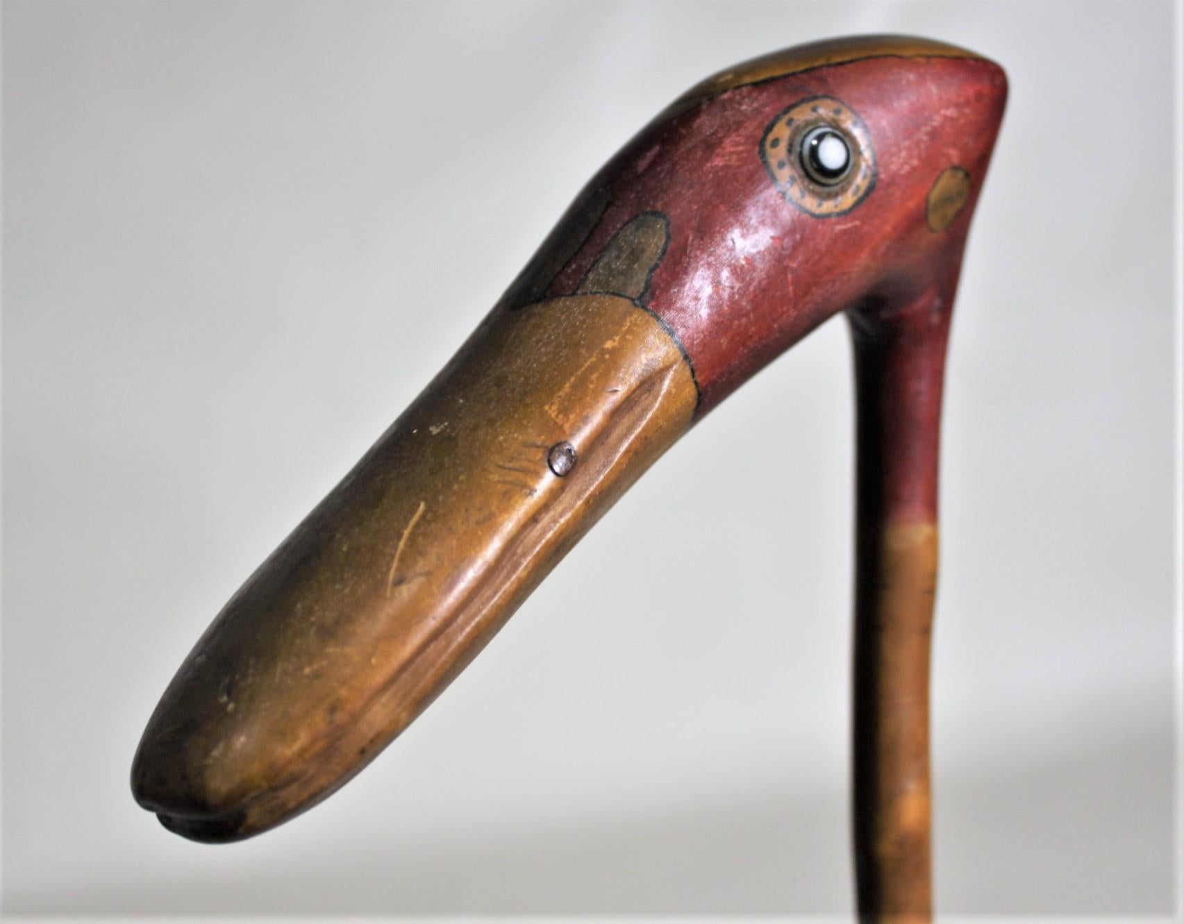 This unique and whimsical Folk Art walking stick is unsigned, but presumed to have been made in the United States in approximately 1930. The handle of this cane has been hand painted and hand carved to resemble an exotic bird or animal of some sort