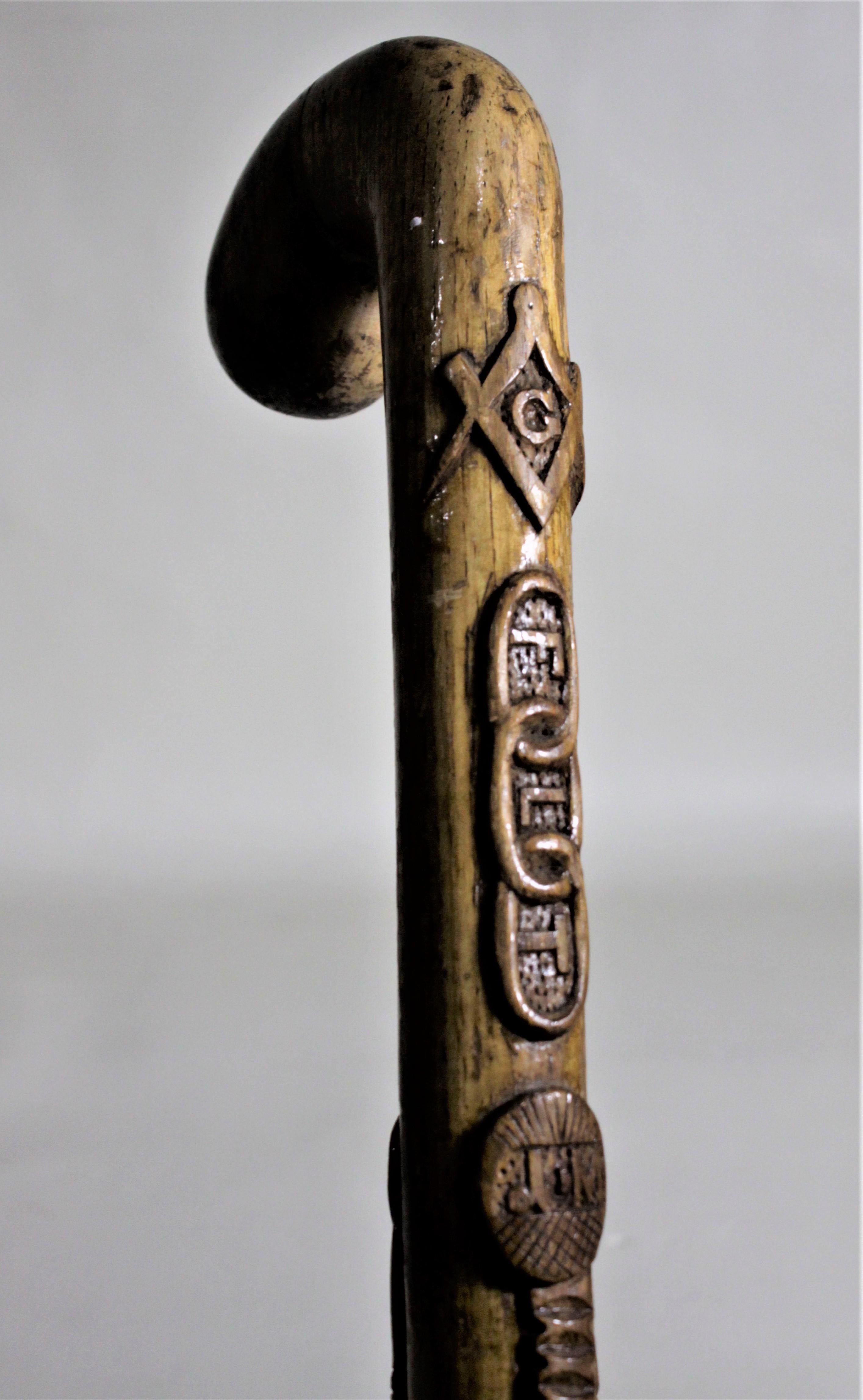 This antique Folk Art deeply hand carved walking cane most likely dates to the late 19th century and originates from Scotland or England. The cane is very intricately carved with the freemason's symbol at the top followed by a depiction of the