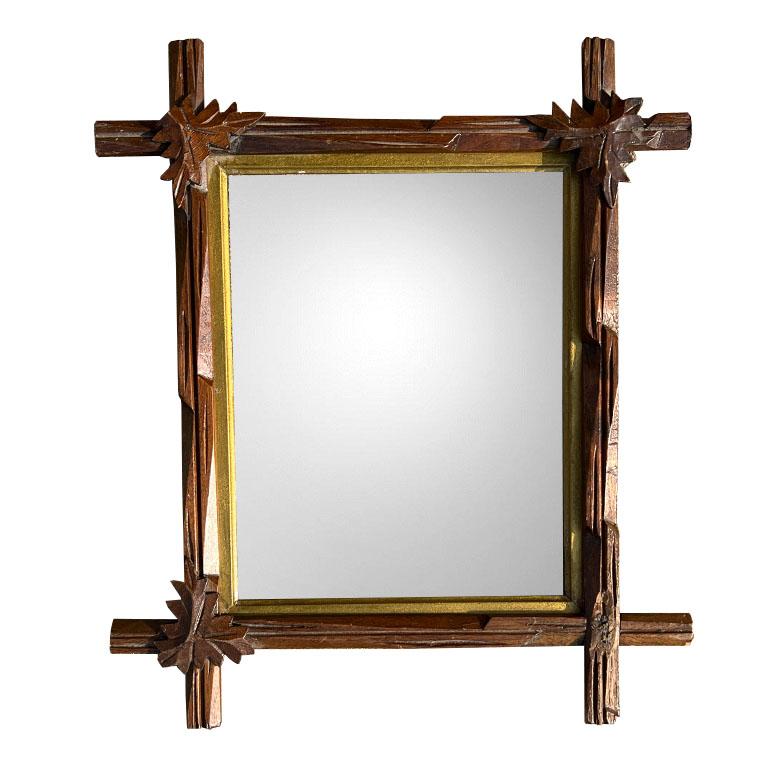 Antique and hand-carved in dark brown wood, this tramp art mirror is sure to make a statement in any space. At the joints, each side overlaps in a cross or Adirondack style. Carved marquetry leaves sit upon each joint. (With the exception of one