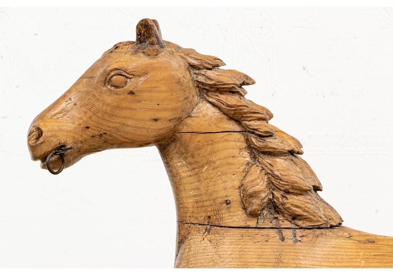 A very fine Folk Art carved wood Horse in very good condition. The very animated and prancing horse made in separate pieces for the head, legs and tail, attached with dowels. The mane and tail with fine wavy hair. It has dark stained ears and metal
