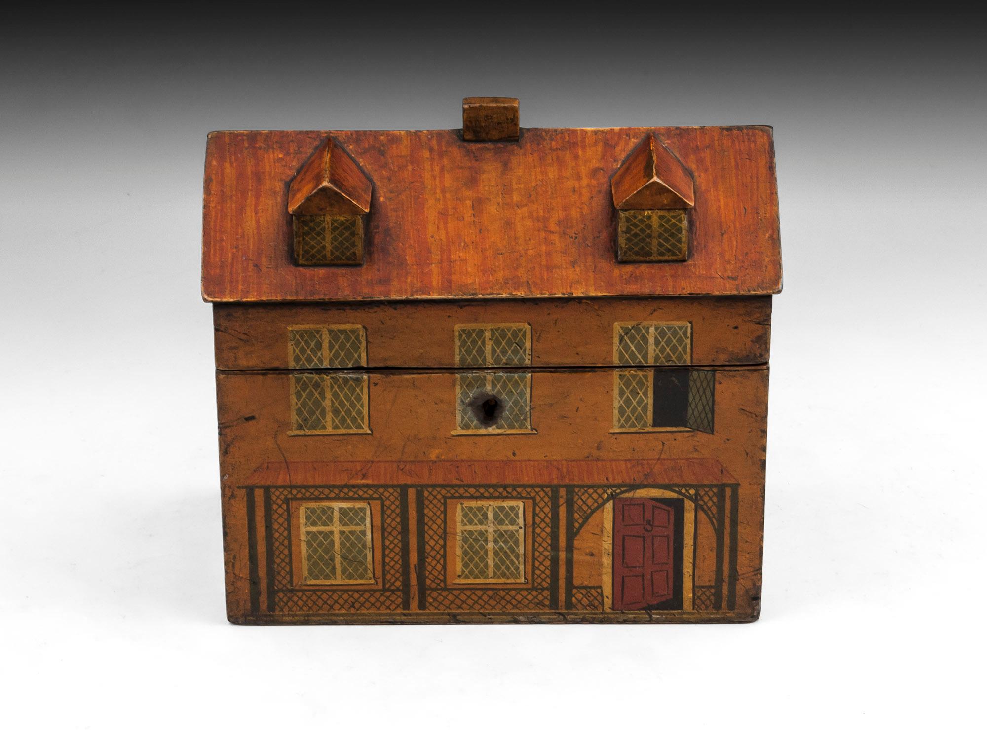 Rare Folk Art tea caddy in the form of a country cottage. The exterior of this delightful charming house tea caddy is adorned with painted windows, doors and surrounding plants. 

The interior of the cottage tea caddy features two lidded