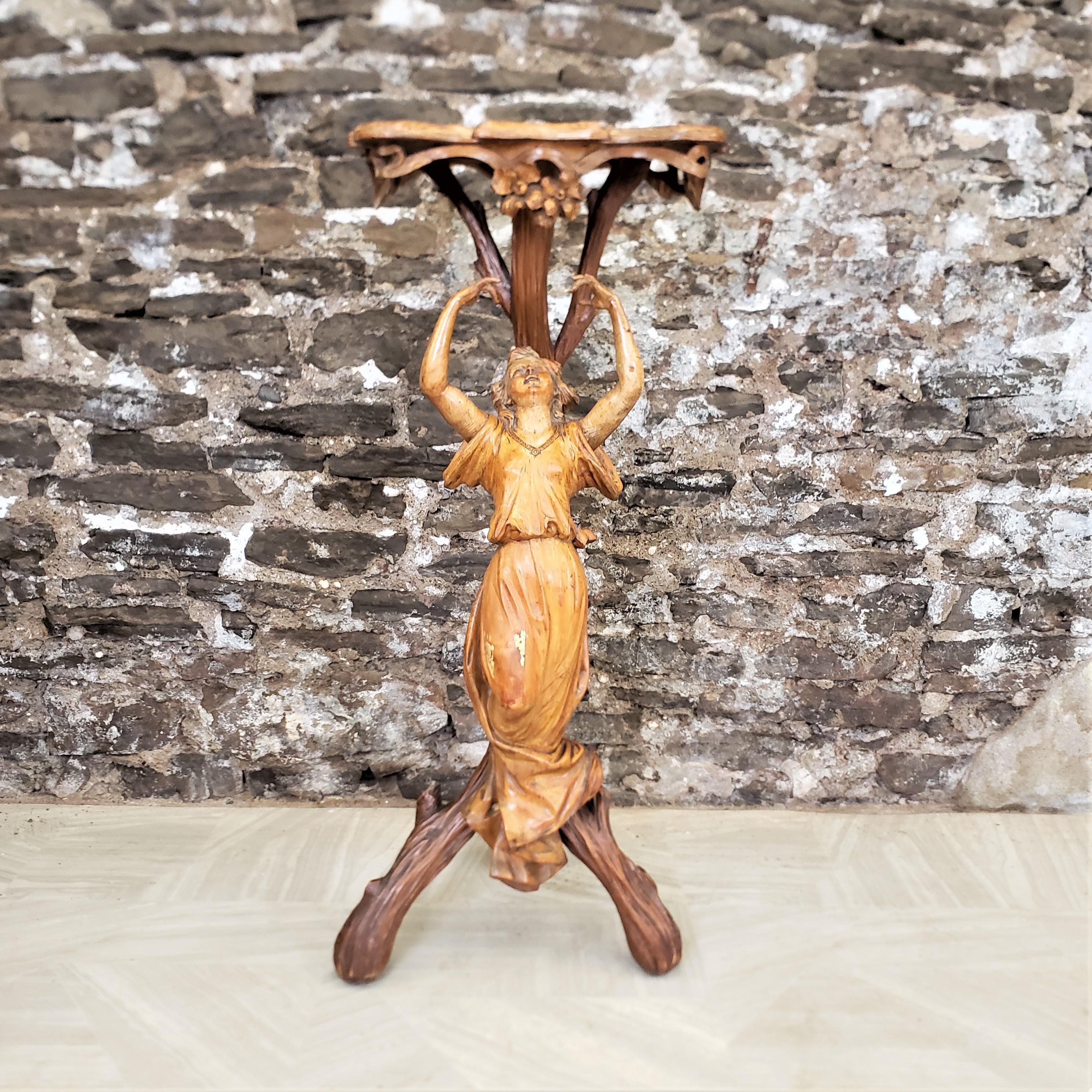 This antique pedestal table is unsigned, but presumed to have originated from Italy and date to approximately 1900 and done in the period Art Nouveau style. The table is composed of a grape vine wooden base with a hand-carved woman with outstretched