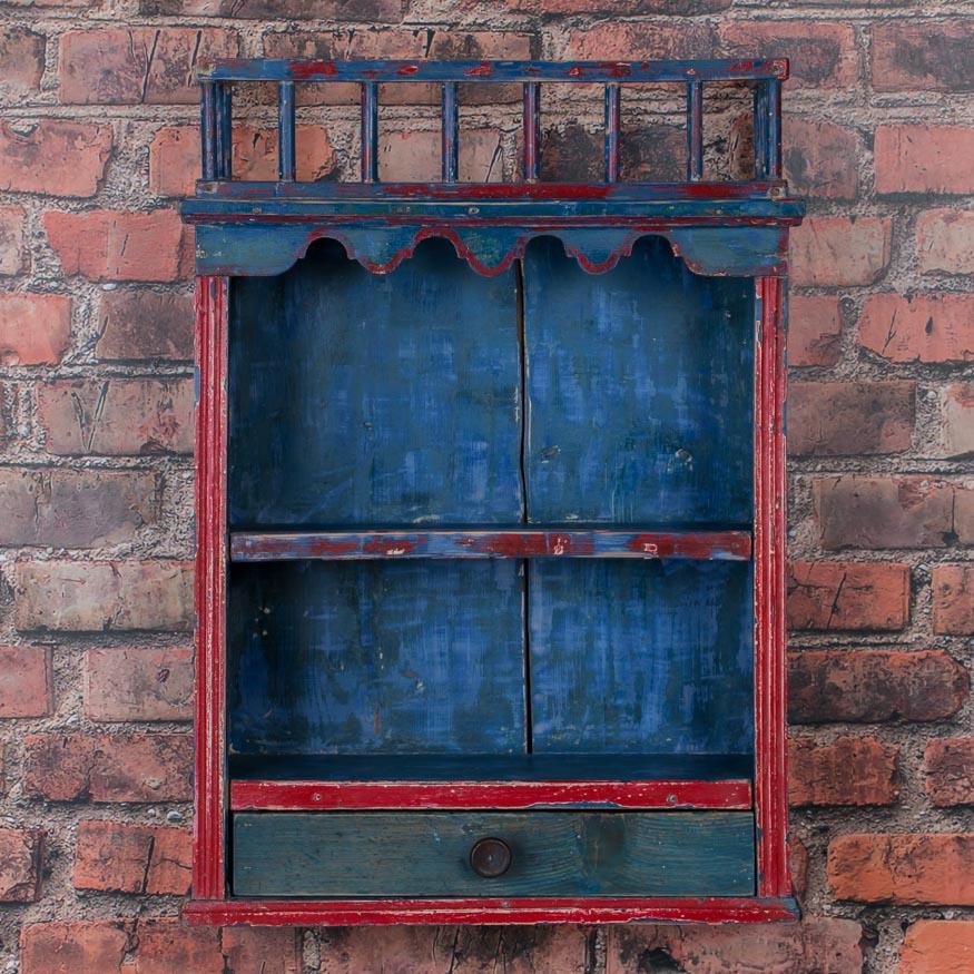 The bright blue background and red flowers and trim draw ones eye to this beautifully restored antique hanging wall rack from Hungary. Originally used in a country home to hold and display plates and bric-a-brac on it's shelves, this piece would be