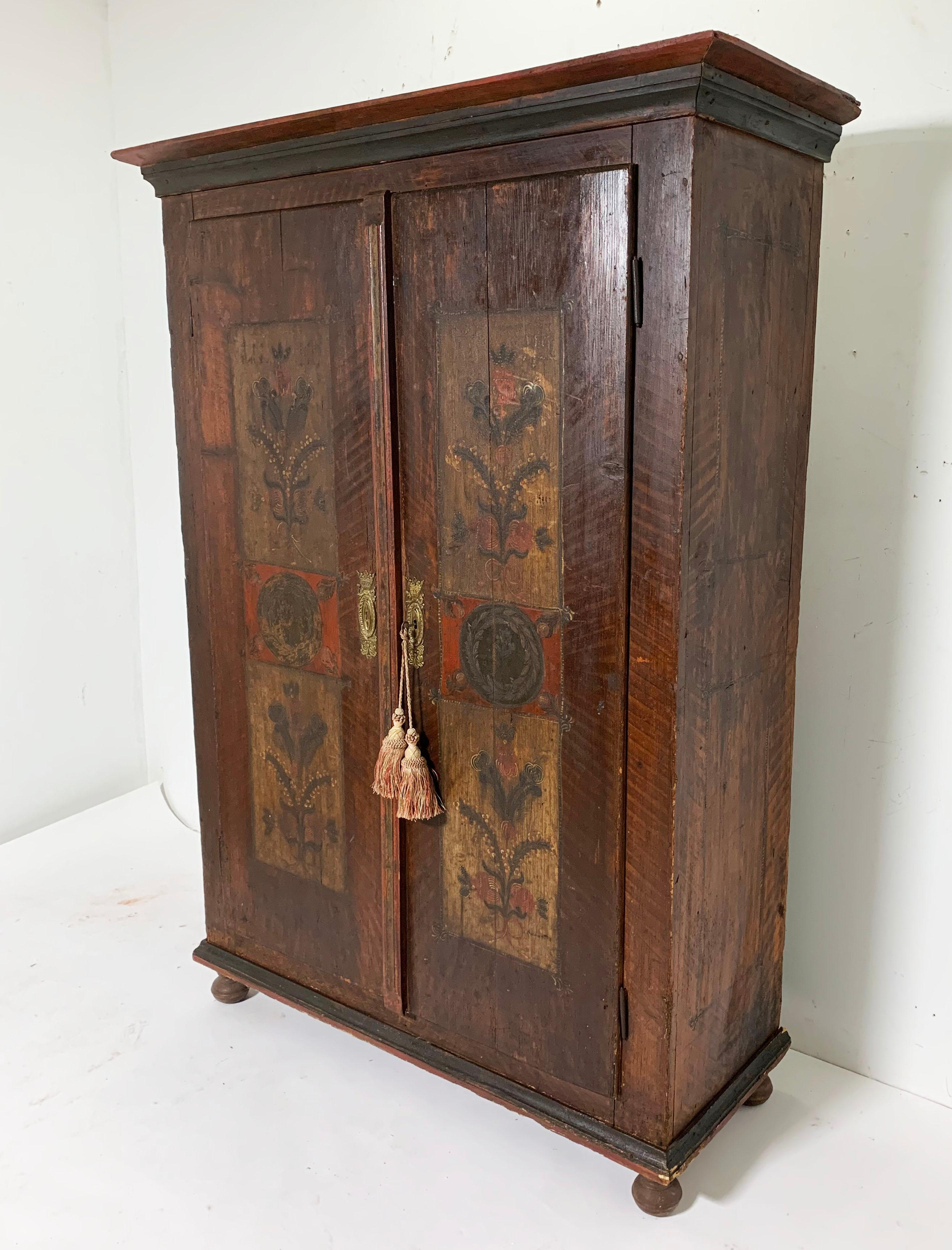 A Folk Art painted Austro-Hungarian two-door standing wardrobe. The chest itself was likely constructed in the 1700s and presented as a dowry or wedding gift in 1842, as dated on the right-hand door. The door panels are painted with floral motifs in