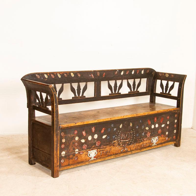 This wonderful pine bench still retains the traditional folk art paint of the era, with simple floral motifs painted on an earth-toned base such as this one. Reflecting decades of use, the paint along the seat has been virtually worn away as well as