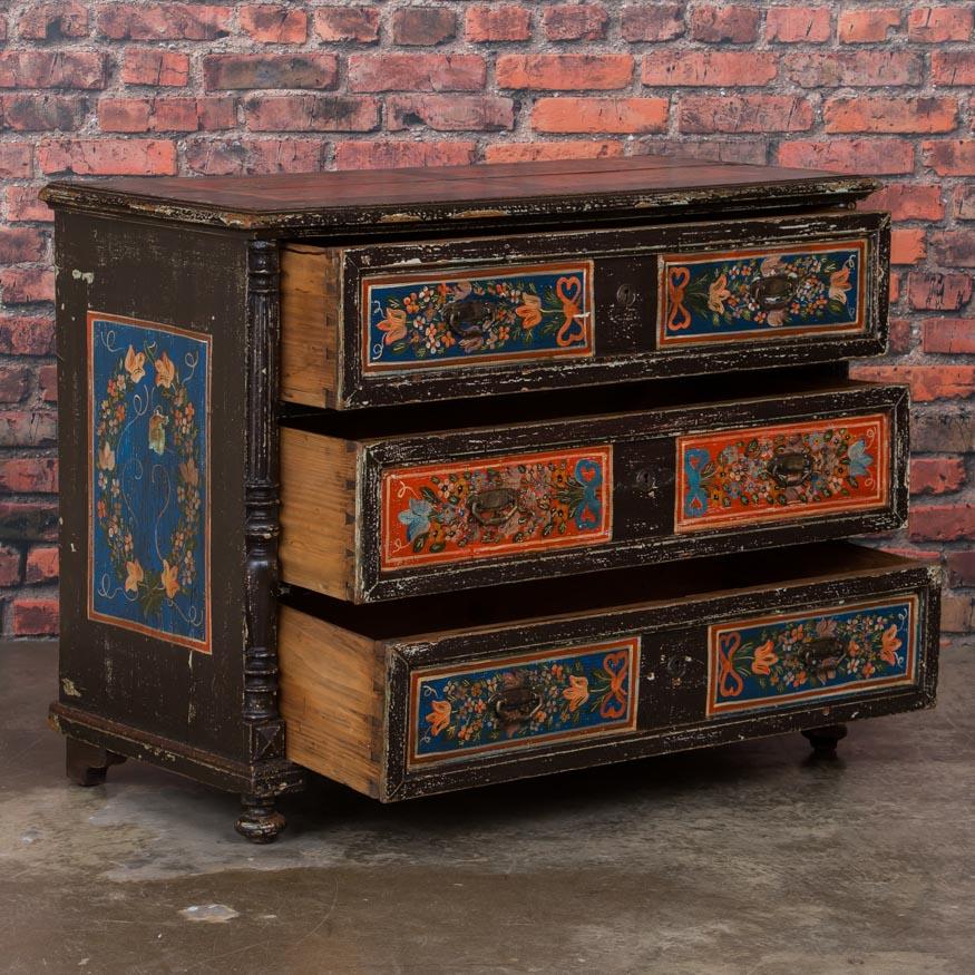 The vibrant colors are all original on this painted antique chest of 3 drawers from Hungary. The blue with orange, green and white floral embellishments were traditional Folk Art designs during the 1800s. The whimsical flowers and bright colors