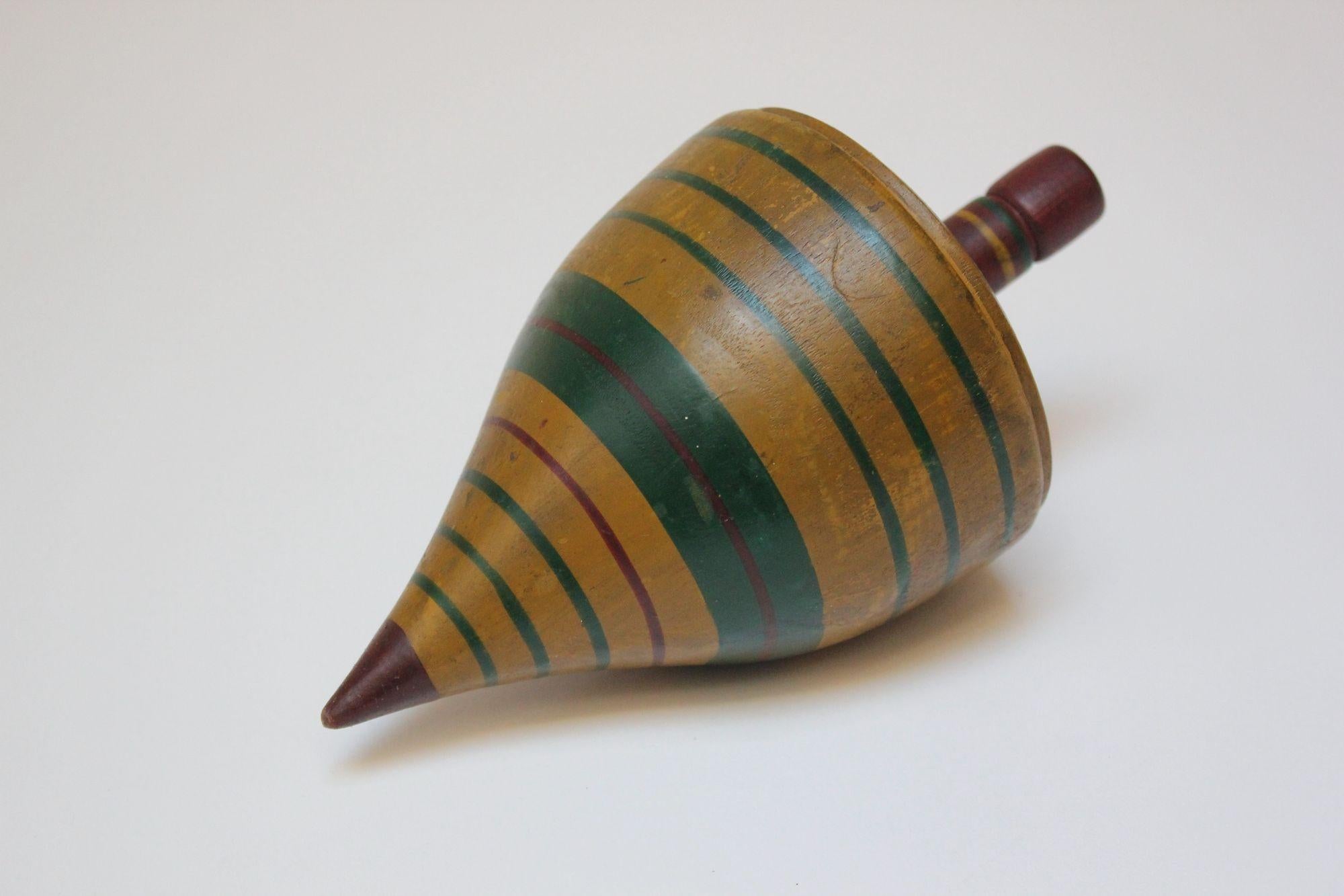 Folk Art turned and painted wooden toy top retaining its original paint (ca. late 19th Century, USA).
Features a notched stem and striped multi-color design in yellow, green and red.
Very good, antique condition with patina/light scuffing and minor