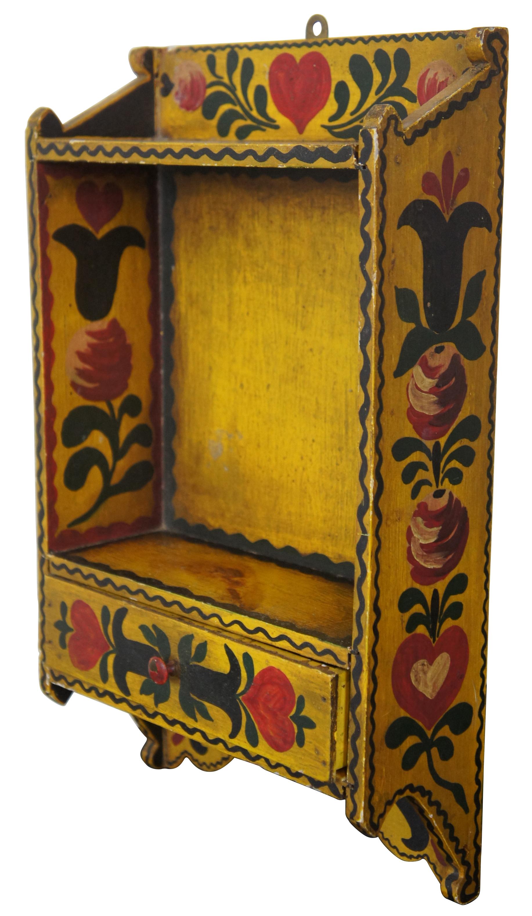Antique wooden wall hanging shelf with drawer, painted with a yellow, green and red Folk Art floral design, marked “Todds” on the reverse.
  