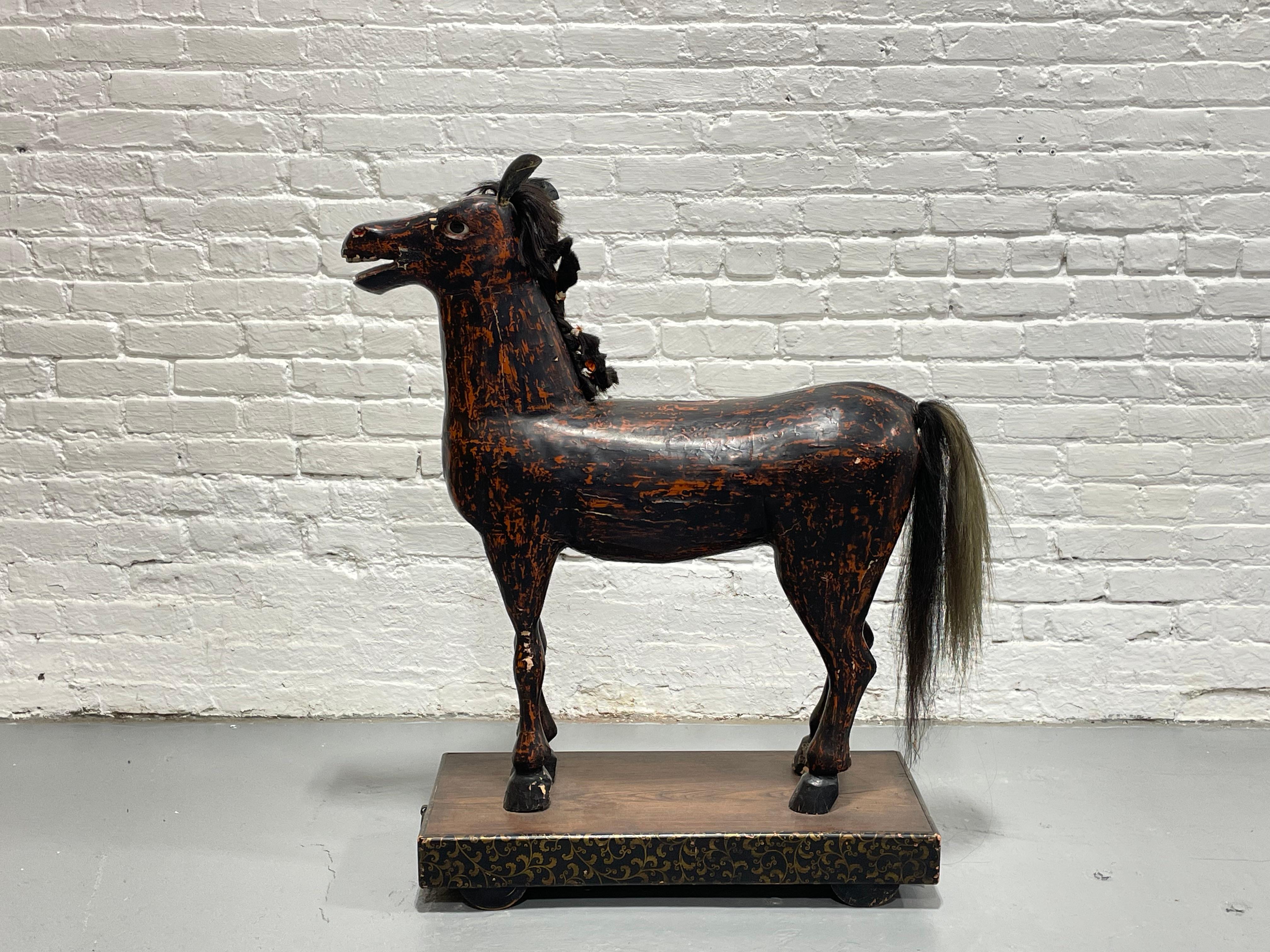 Antique Original Folk Art Ride On Wooden Horse on Platform with Wheels, c. 1910. A stunningly handsome piece which stands on the original platform with functioning wheels. Painted on carved wood, gesso, and paint with horsehair and glass eyes;