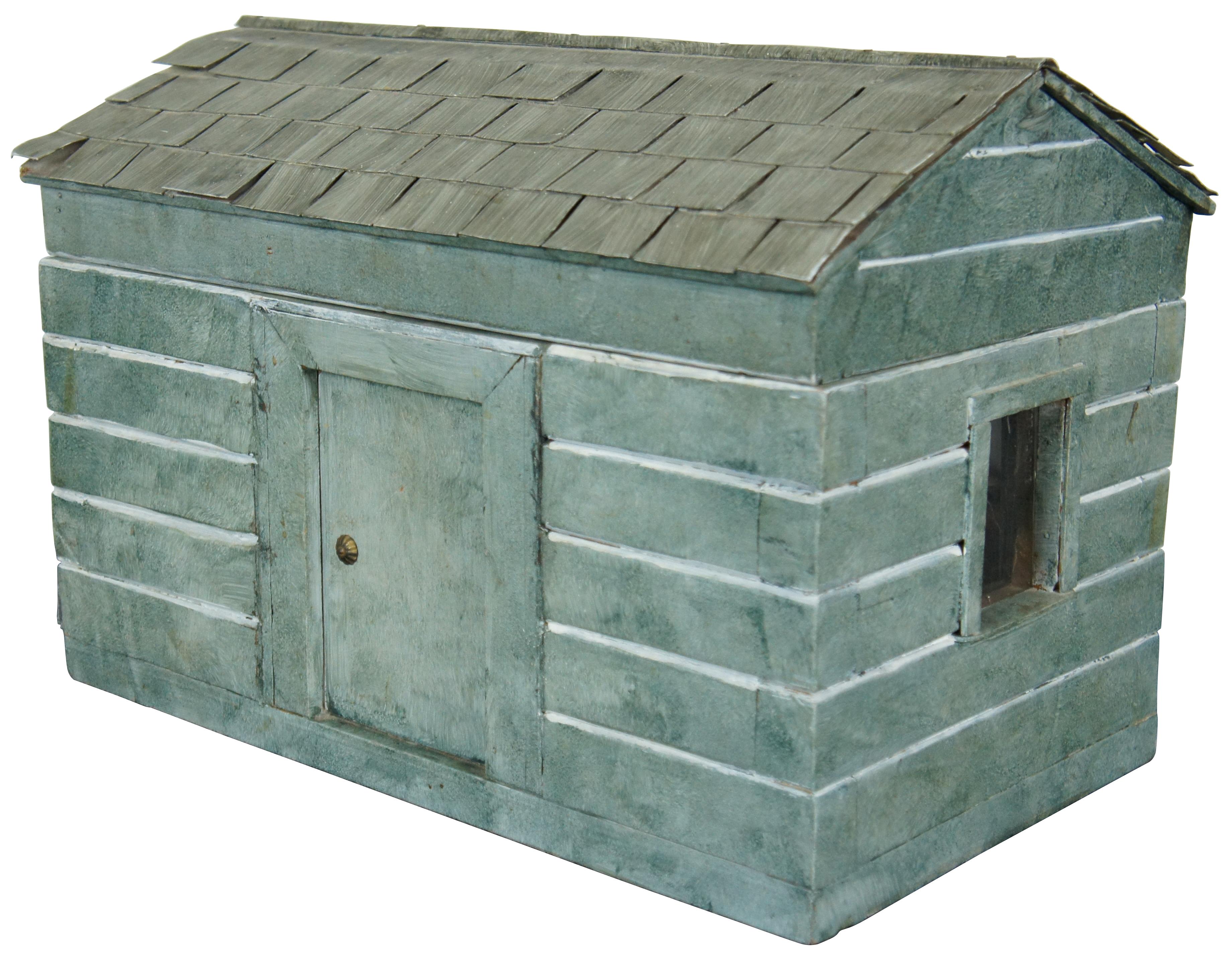 Rare and antique folk art doll house box or toy chest in the shape of a rustic green cabin with two glass windows and a shingle roof.
 