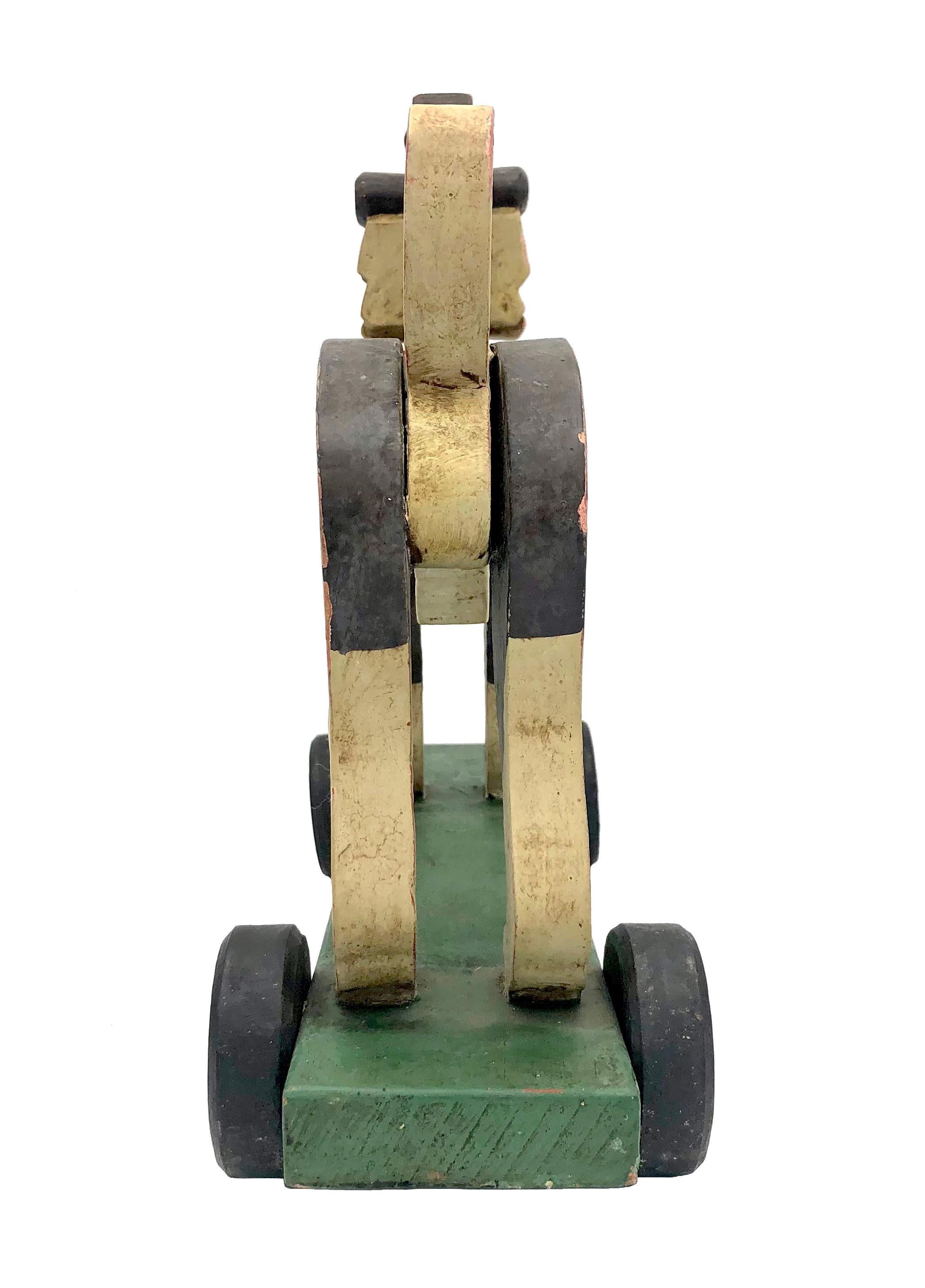 This beautiful double sided beagle is made out of carved wood and has been hand painted. It is fixed onto a green wooden base with four wheels.
The paint has worn off on some of the edges but the dog remains in remarkable fresh condition for it's