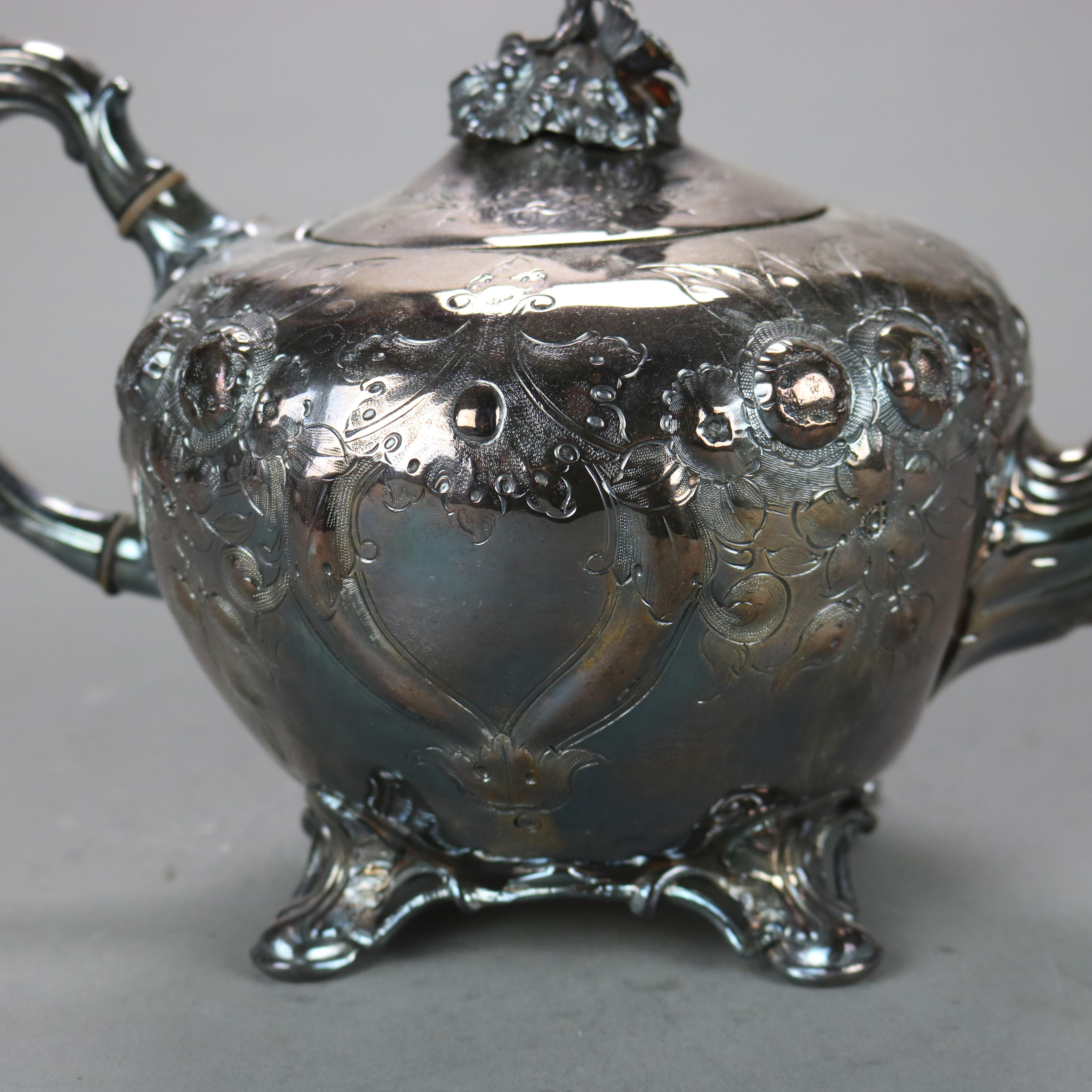 Théière ancienne à pied en métal argenté avec gravure de feuillage et de fleurs C1890

Mesures - 6.75 