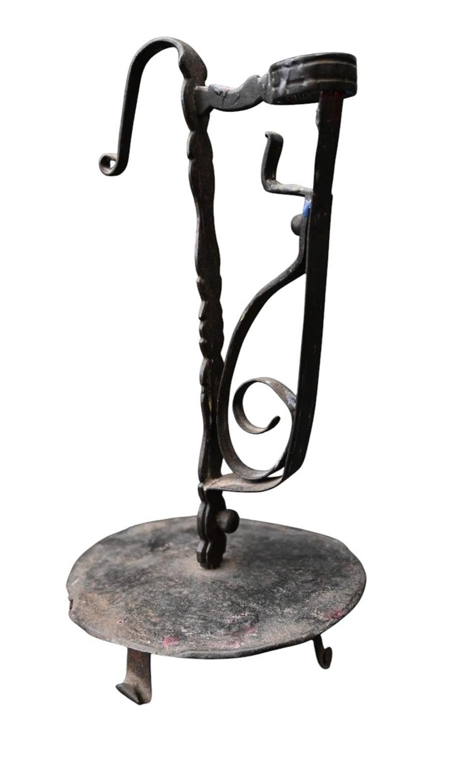 Rare chandelier en fer forgé à la main, datant probablement du 17e siècle, avec de belles volutes et une base tripode pratique. Entièrement réalisé à la main par un forgeron, il présente un plateau circulaire, une tige torsadée et une coupelle à
