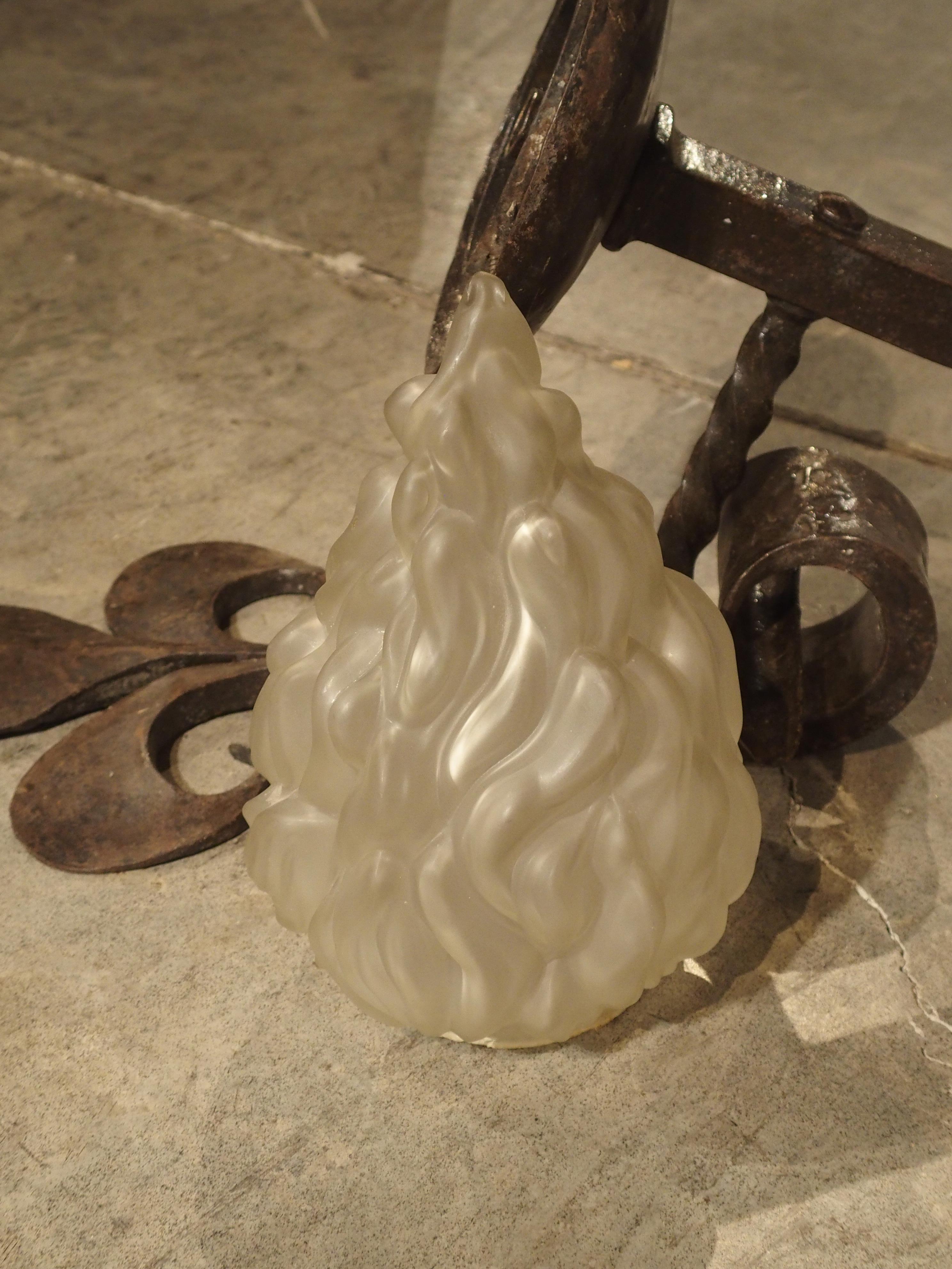 Originaire de France, cette applique ancienne en fer forgé de style torchère est ornée d'une grande fleur de lys unique en haut et d'une épaisse volute en bas. La tige de l'applique est inclinée et maintenue sur la plaque arrière par une barre de