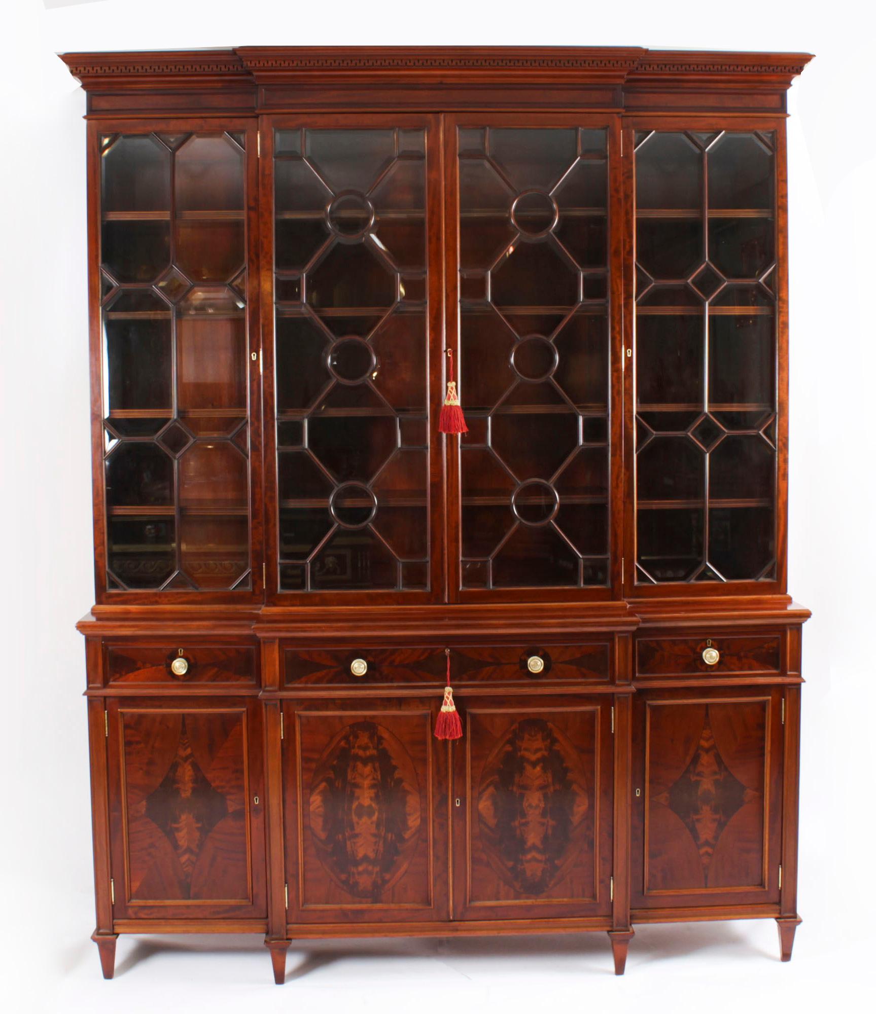 This is a beautiful antique top quality  Sheraton Revival  flame mahogany four door breakfront bookcase, masterfully crafted in rich  mahogany by the world renowned London cabinet makers, Edwards & Roberts,  Circa 1890 in date.

The bookcase