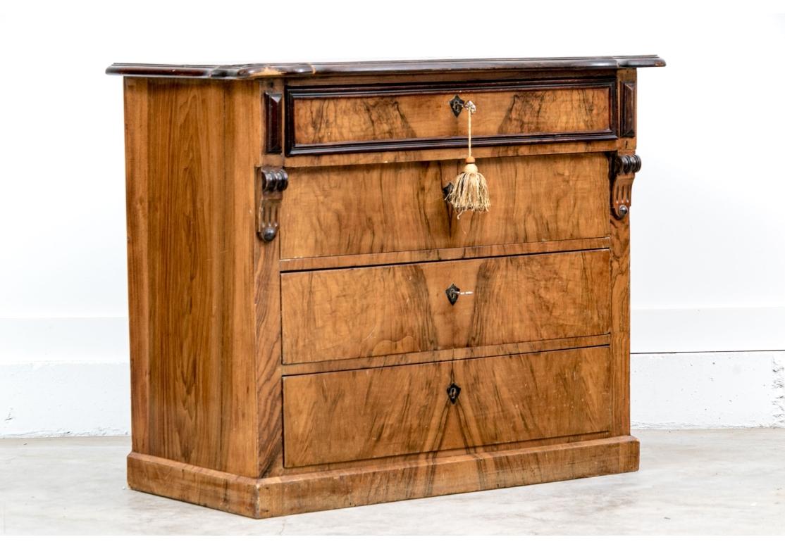 Eine feine Kommode mit vier Schubladen aus europäischem Nussbaum-Maser mit einem geformten Oberteil mit einer dunkleren geschnitzten Kante. Die Fries-Schublade hat dunkle geschnitzte Leisten und Wappen, und die Stützen haben auch dunklere