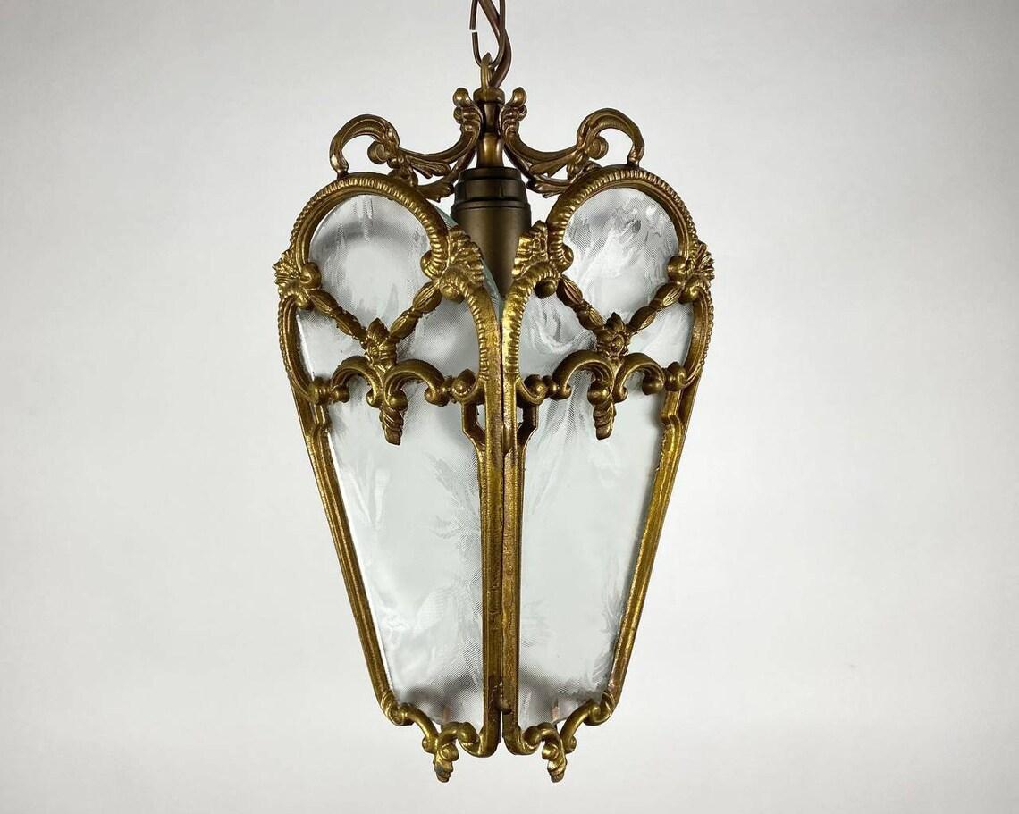 Antique 4-sided Ceiling Lantern for one light bulbs. France, 1920s.

A delightful antique ceiling chandelier/lantern in the style of pendant lamps of the XIX century.

The frame is made of brass, decorated with three-dimensional patterns and