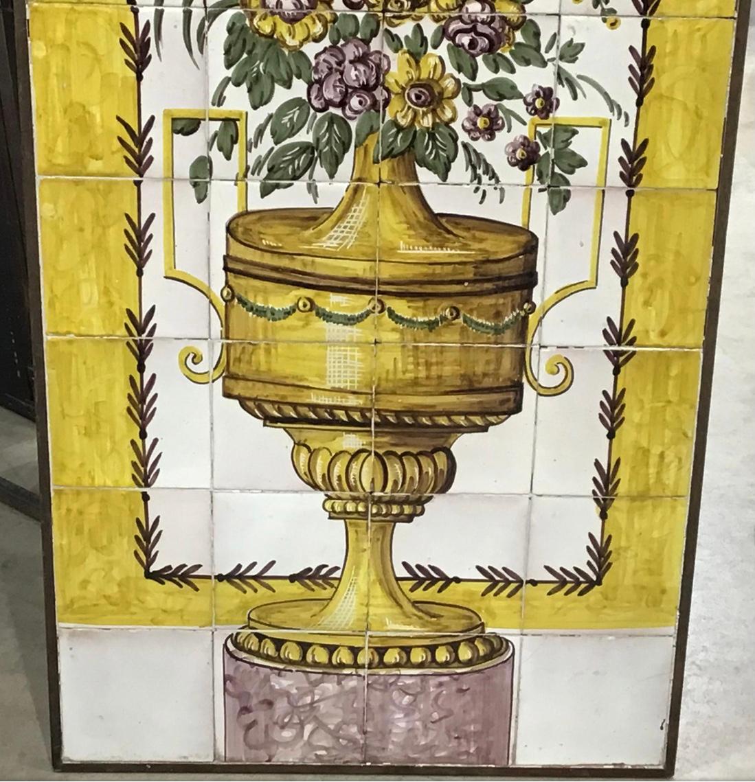 A set of framed hand painted tiles. Probably Spanish or Italian. Hand painted showing an urn on a pedestal with a bouquet of flowers. Mounted in a wood frame with heavy wire for hanging.