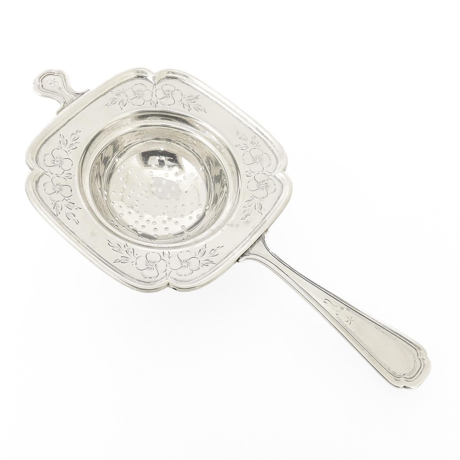 Un raffinato colino da tè antico.

In argento sterling.

Di Frank M. I. Whiting.

Con una ciotola a forma di quatrefoglio con un manico corto e uno lungo e fiori di ciliegio incisi.

Sul retro è presente il marchio Frank M. Whiting / Sterling / un