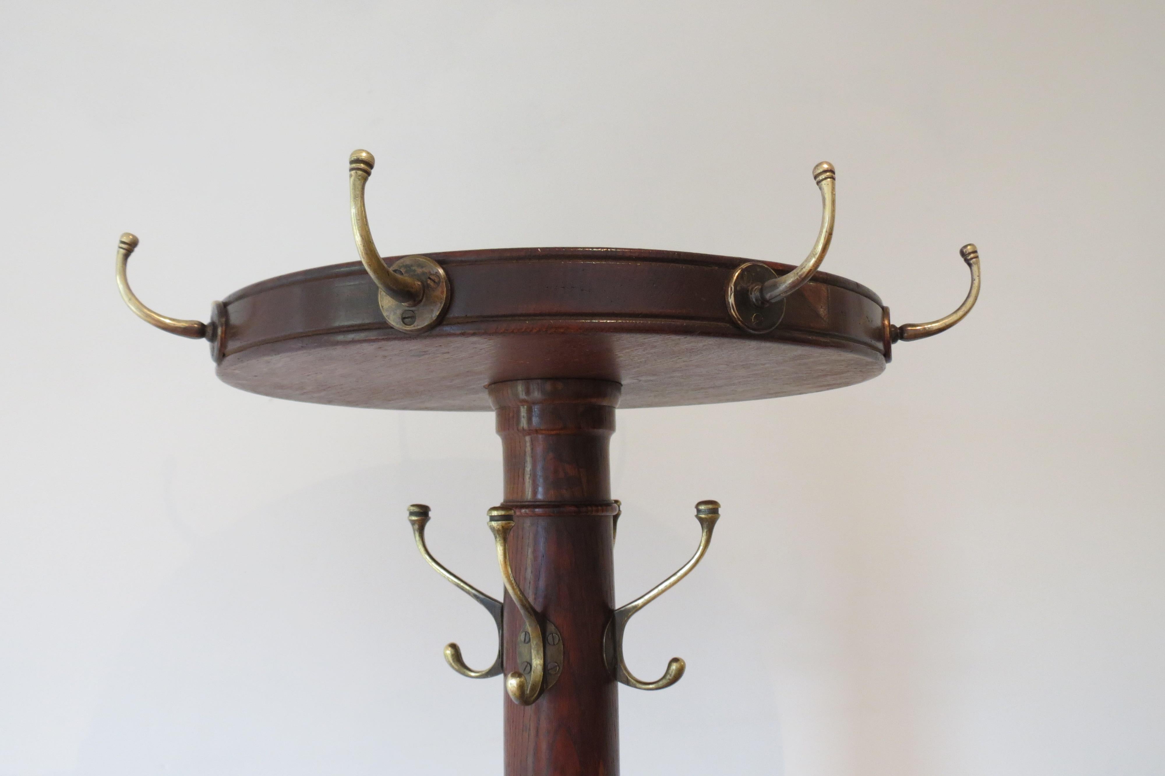 An antique freestanding coat rack, exceptional quality. Made from Oak and solid brass fittings. The top section with hooks swivels allowing easy access to hanging coats. The large solid brass ring allows umbrellas and sticks to be stored