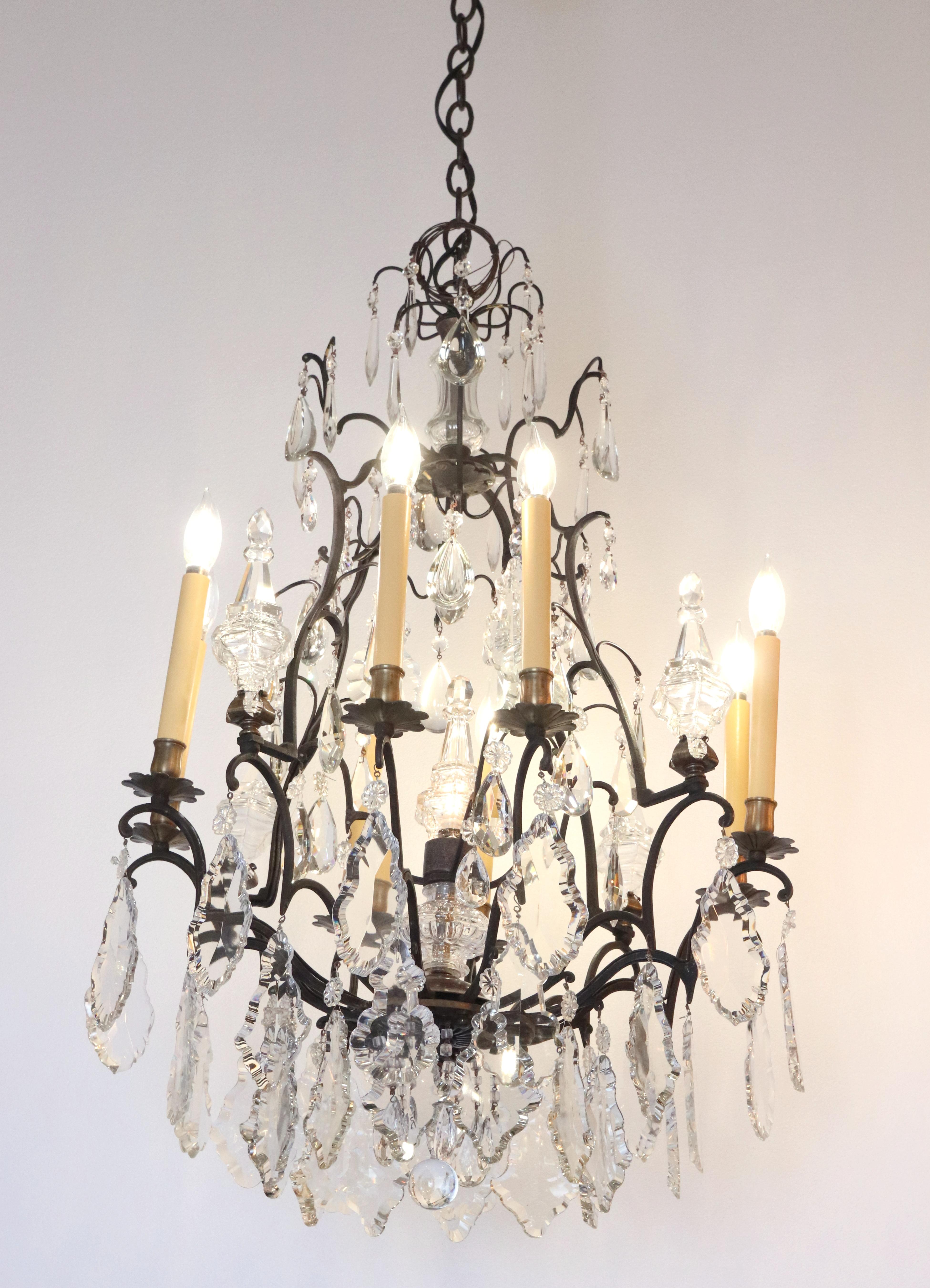 Lustre ancien à 12 bras de style français, drapé de cristaux clairs en forme de pendeloques, sur une monture en bronze peinte en noir. Elle a été acquise dans une résidence de la fin du 19e siècle située à Brooklyn Heights, New York. Cette lampe