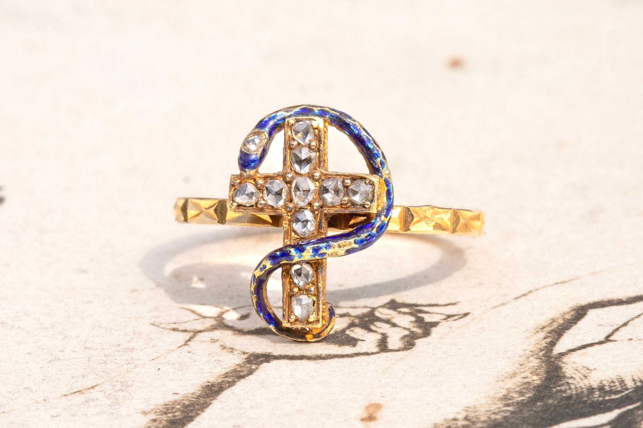A wonderful antique enamelled snake and cross ring. This piece probably started life as a stickpin dating to the second half of the 19th century, circa 1870 and was later been converted into a ring. It is crafted in 18K yellow gold and the serpent's