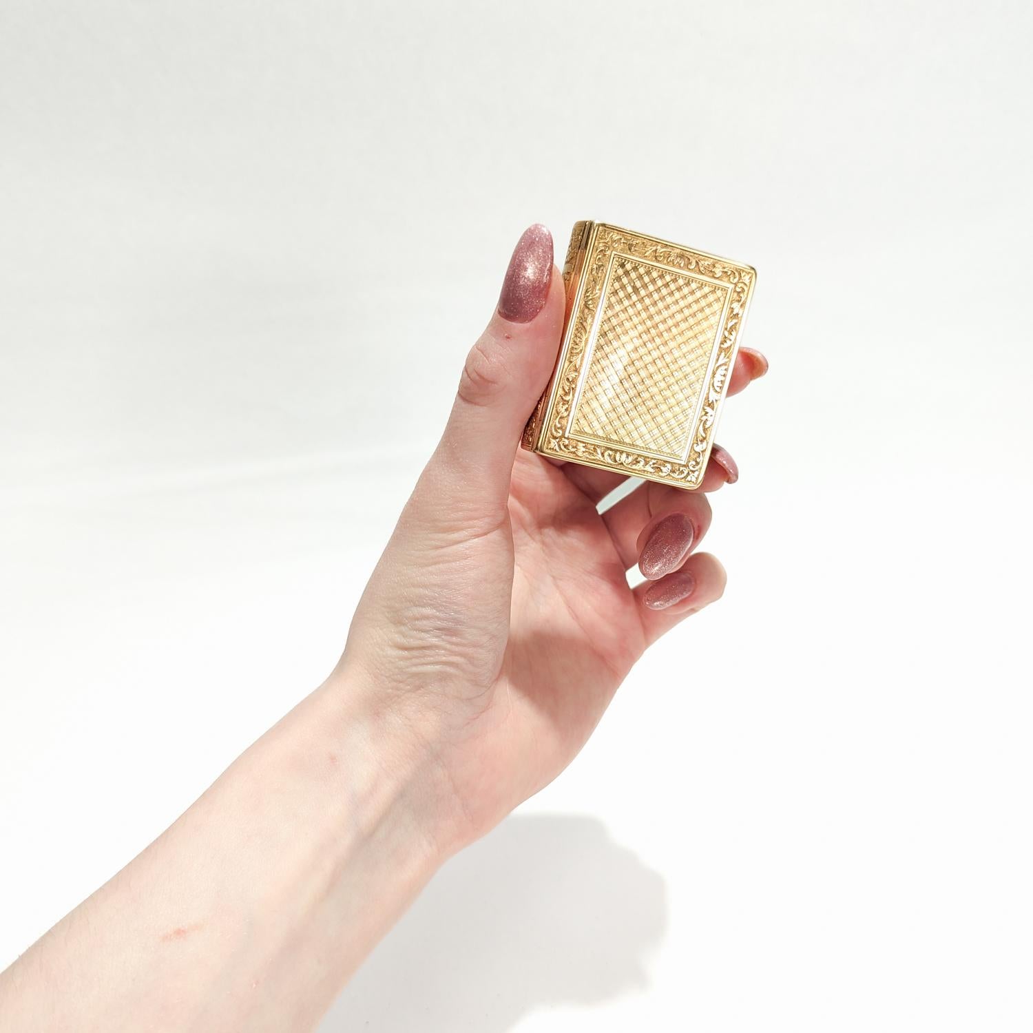 A fine antique French snuff box.

In 18 karat yellow gold.

In the form of a miniature book with embossed leaf work decoration to the edges and engine turned diaper pattern decoration to the center as well as grooved faux paper pages to the