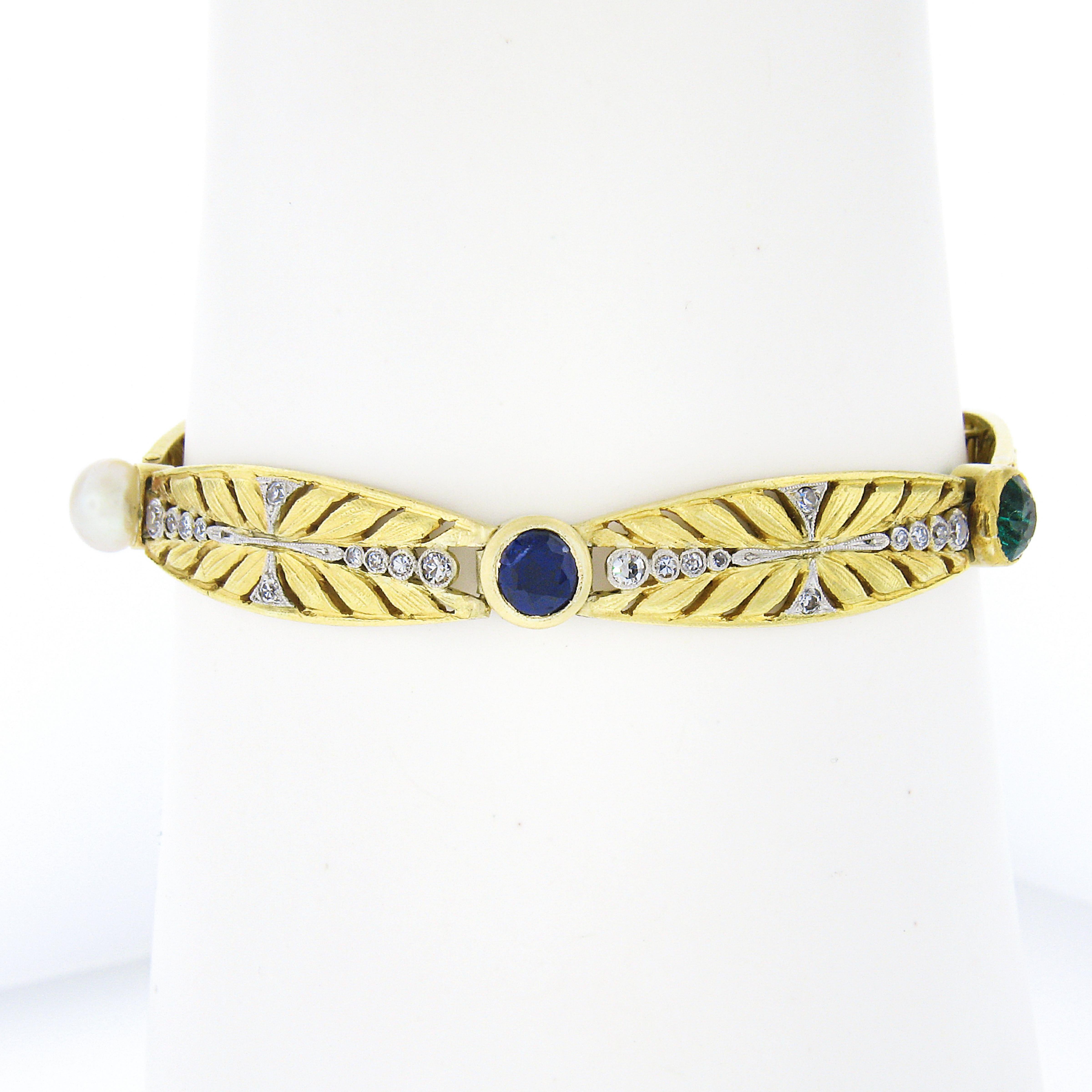 This magnificent and truly elegant antique Edwardian period bracelet was crafted in France from solid 18k yellow gold and features outstanding floral leaf open work links with fine quality sapphires, emeralds, and a pearl neatly set in-between. A
