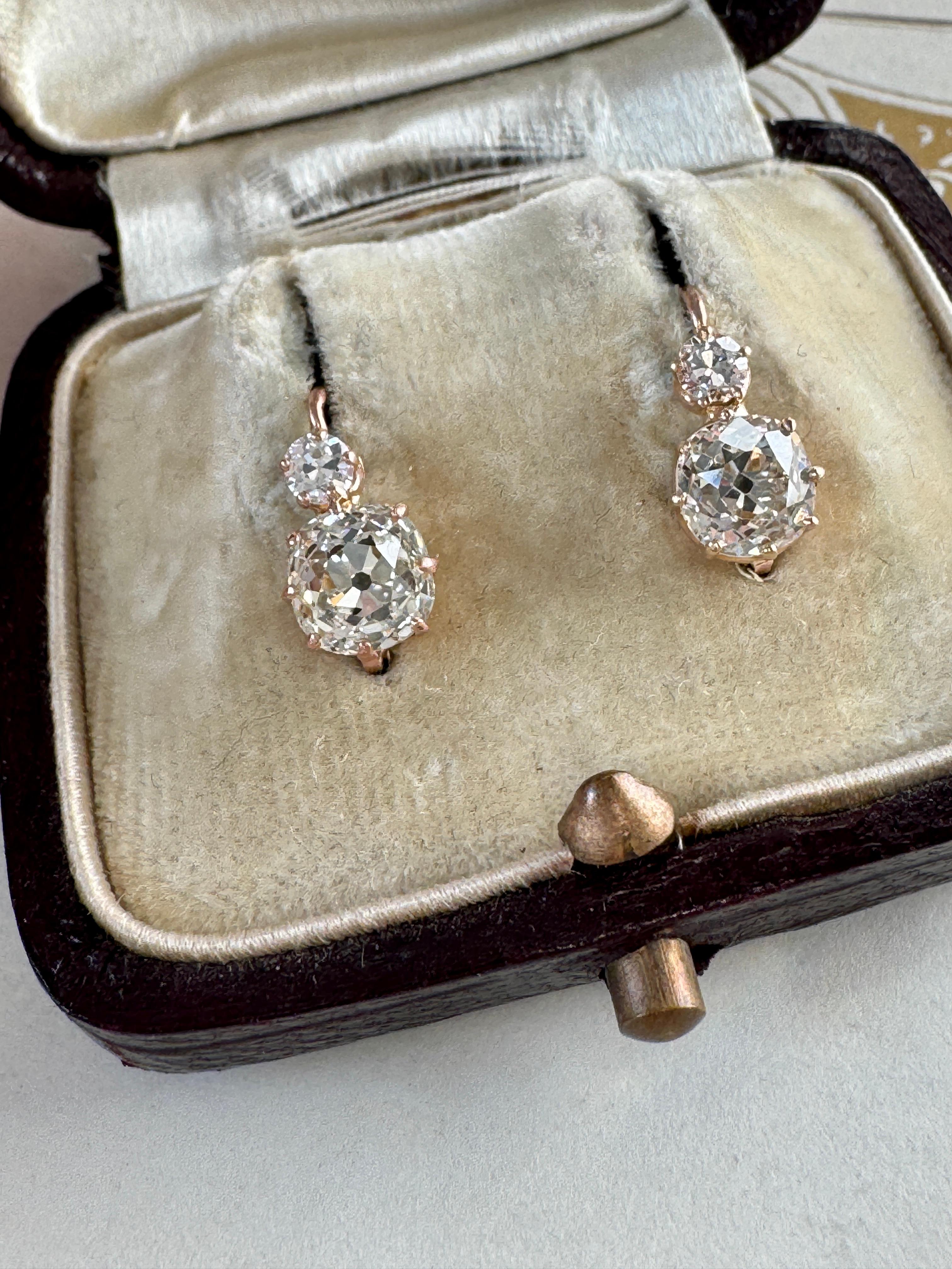 Dating to the turn of the 20th century France, these exquisite earrings proudly display a scintillating pair of chunky old mine-cut diamonds, weighing .99 and 1.20 carats, that rest beneath glittering .10 carat old mine-cut diamonds. These cuties