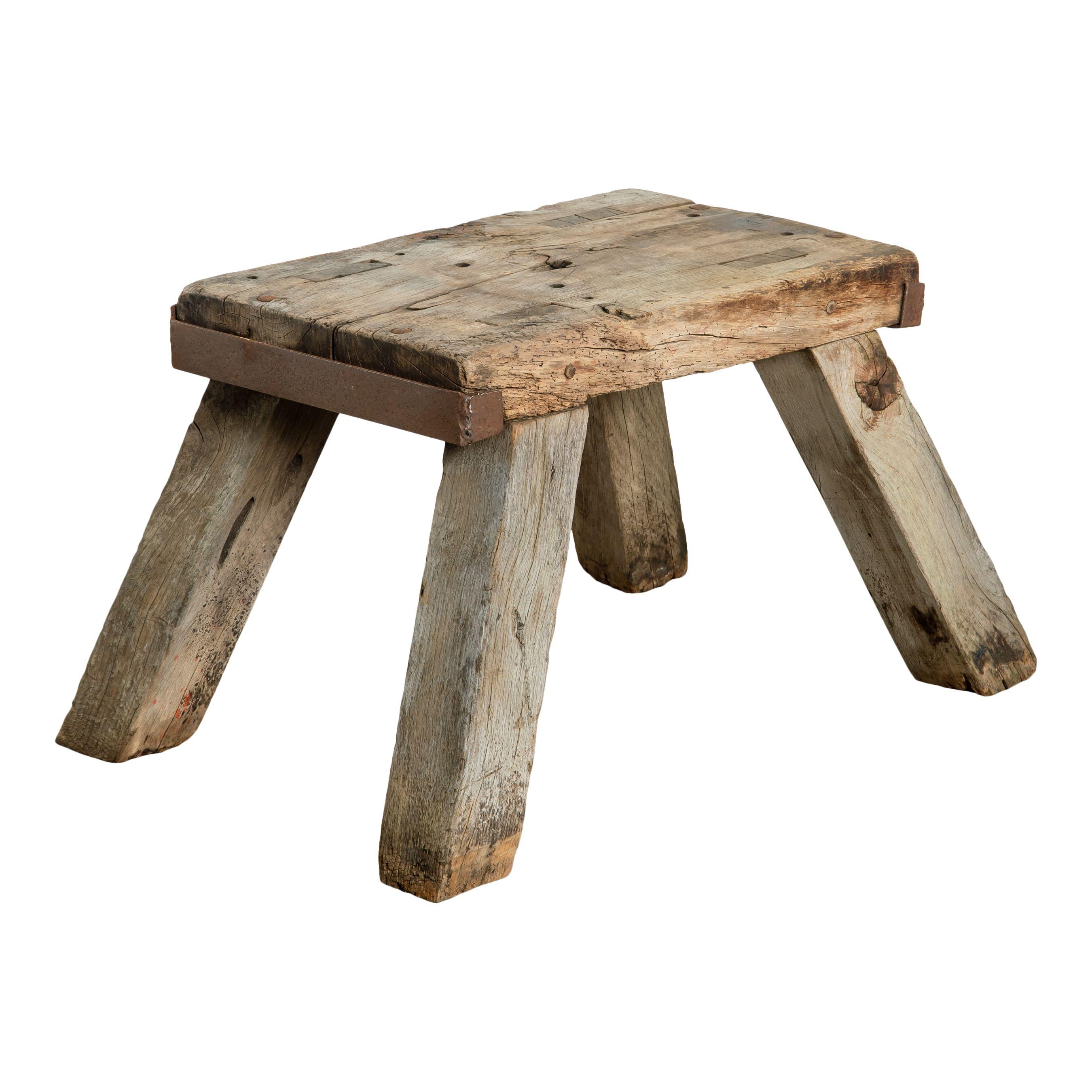 Una sencilla mesa vintage con pedestal de madera en bruto procedente de Francia y fabricada a principios del siglo XX. La sencilla forma rectangular, la madera en bruto, las patas gruesas inclinadas y las esquinas metálicas confieren a esta pieza un