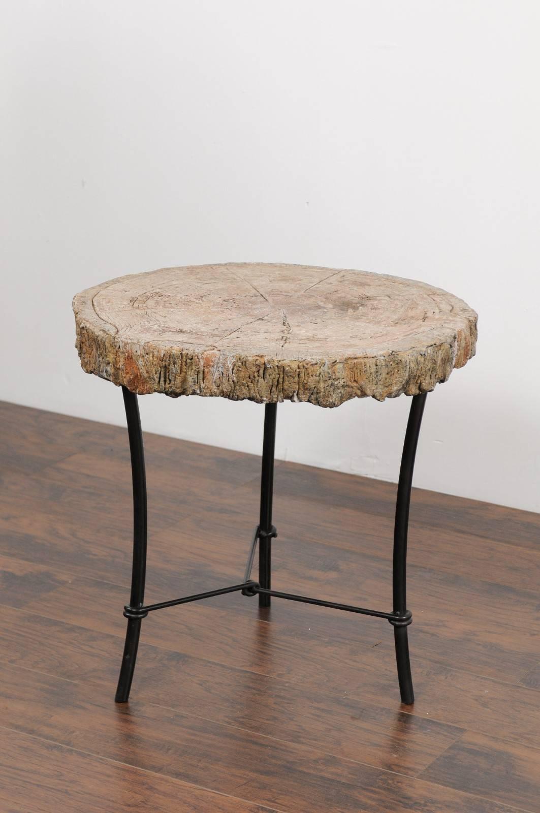 A large French faux-bois stone side table from the early 20th century mounted on a custom iron base. This French side table features a round light-colored faux-bois top, sitting above a custom-made iron base made of three splayed legs connected to
