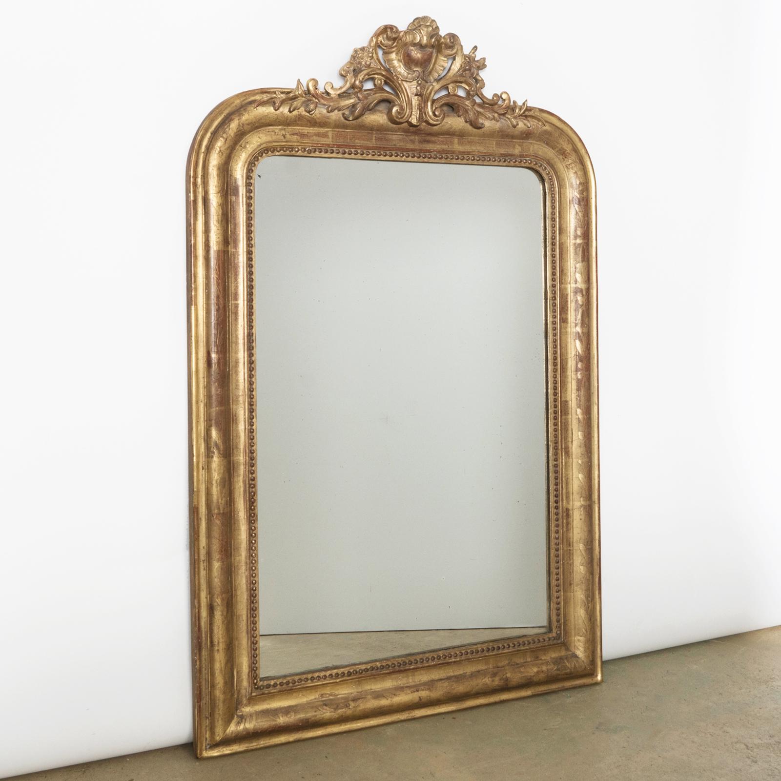 Antique French 19th Century Louis Philippe style gold gilt mirror with elegant small crest.

This beautiful antique French gold gilt mirror has the typical rounded upper corners that make it a Louis Philippe mirror.

The mirror has its original