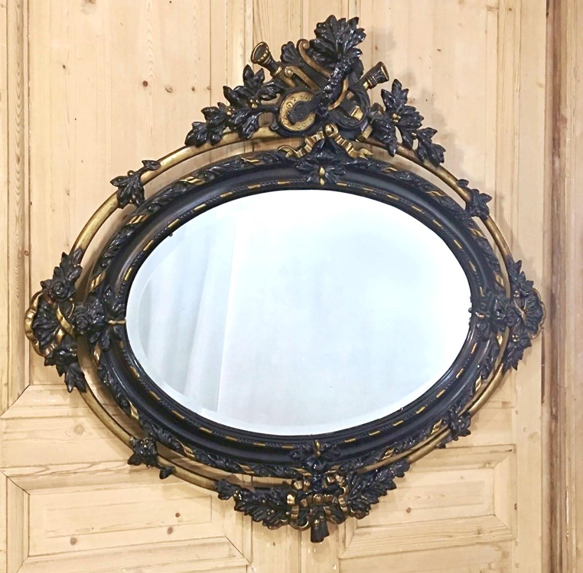 Créé dans une forme ovale horizontale peu commune, ce magnifique miroir ovale Louis XVI ancien français du XIXe siècle présente des détails spectaculaires de haut en bas !  La couronne au centre du sommet présente des instruments de musique, dont