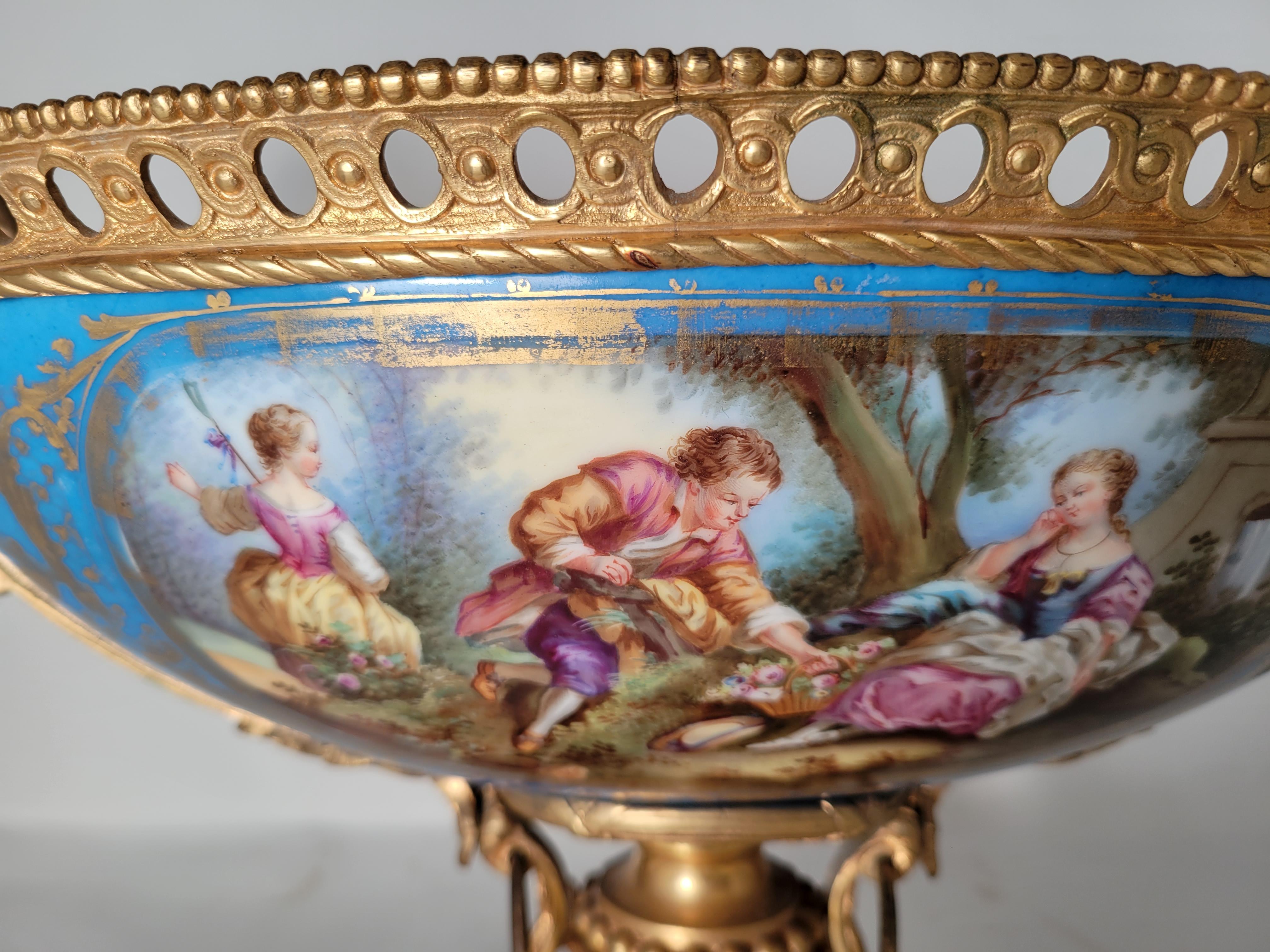 This centerpiece is very beautiful. One side has floral decorative elements and the other, a gentleman bringing a posy of flowers to a lady seated on the ground, while another watches on. The colors are still very vibrant give the age of the piece.