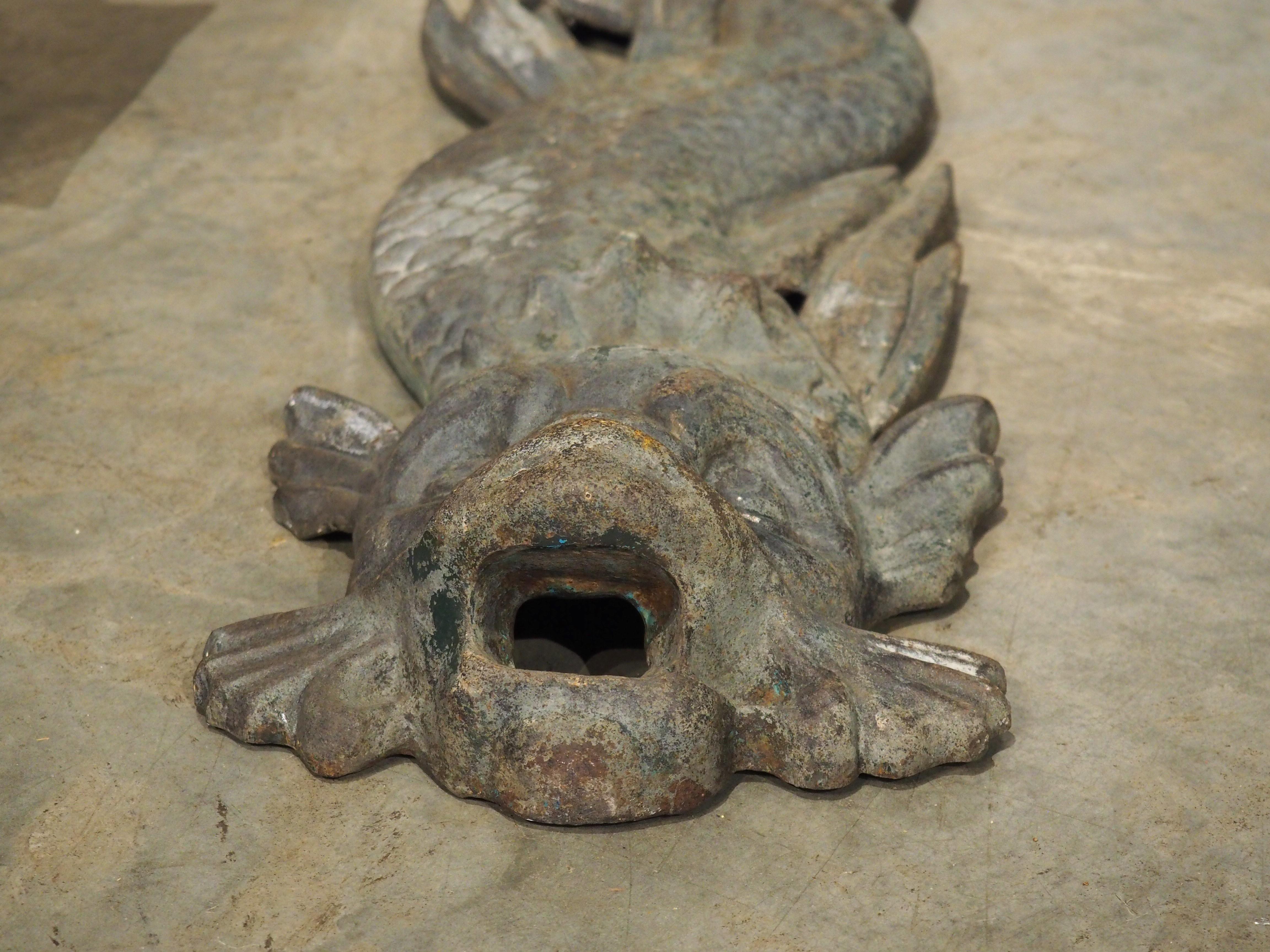 Dating to circa 1900, this French dolphin fountain consists of two pieces of cast iron that have developed a wonderful oxidized and verdigris patina. The vertical dolphin has a rising tail that intertwines around a bouquet of typha (commonly