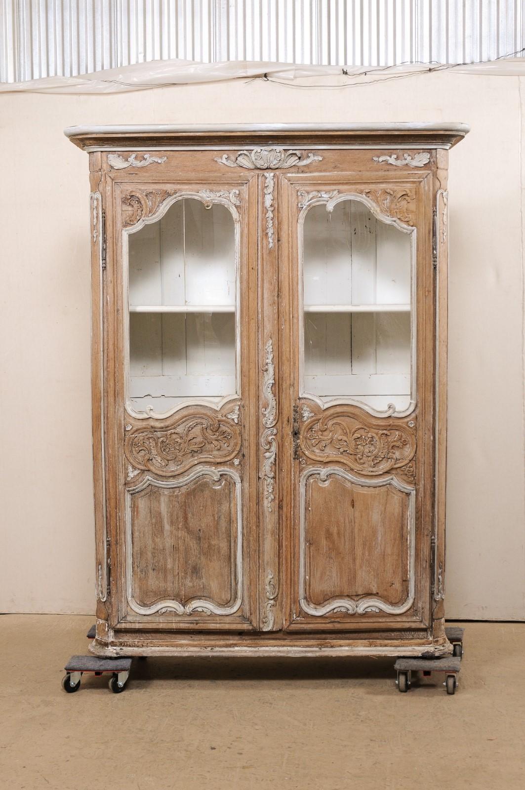 A French tall carved wood and glass panel cabinet from the turn of the 18th and 19th century. This antique cabinet from France, which stands just over 7 feet tall, has been designed with an molded, overhanging cornice, atop a cabinet which houses a
