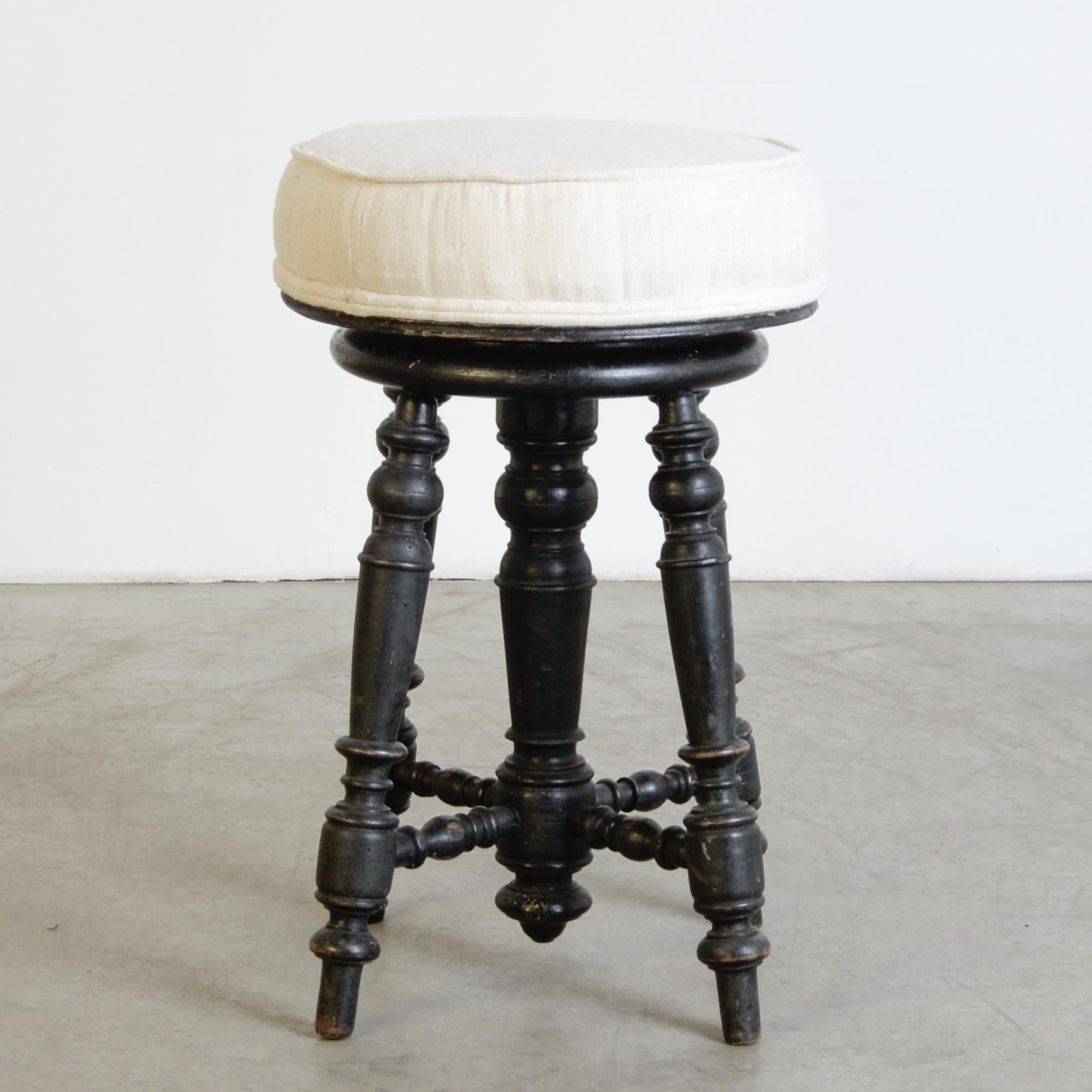 A minimal and decorative French design from circa 1900. Wooden turned legs support a round upholstered seat, rotating up and down with a spinning mechanism hidden inside a central column. Dramatic and reserved black with a great vintage patina,