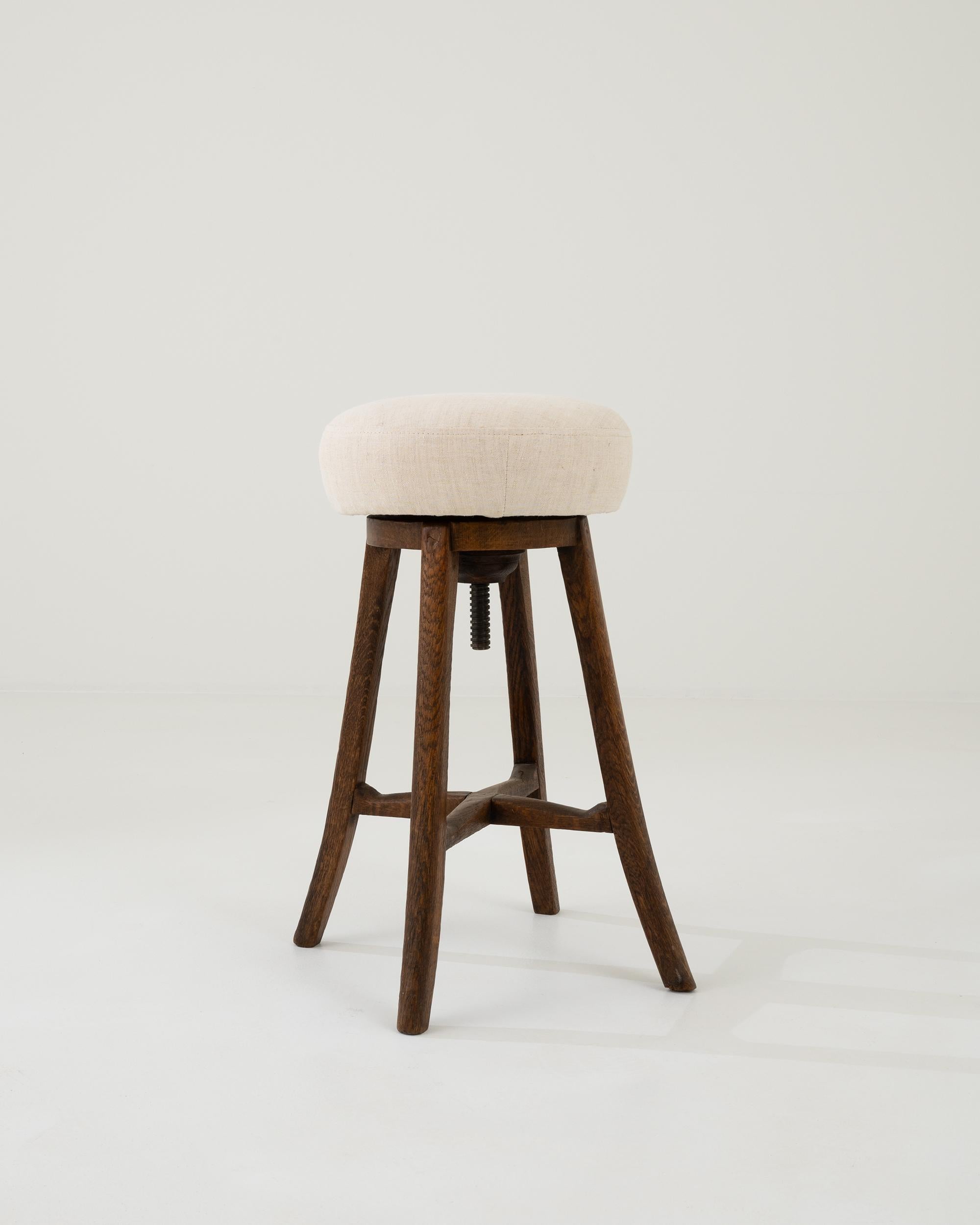 A minimal and decorative French design from circa 1900. Wooden turned legs support a round upholstered seat, rising like a cloud on a large metal screw. A rich brown patina brings out the warmth of the oak, contrasting with the neutral white updated