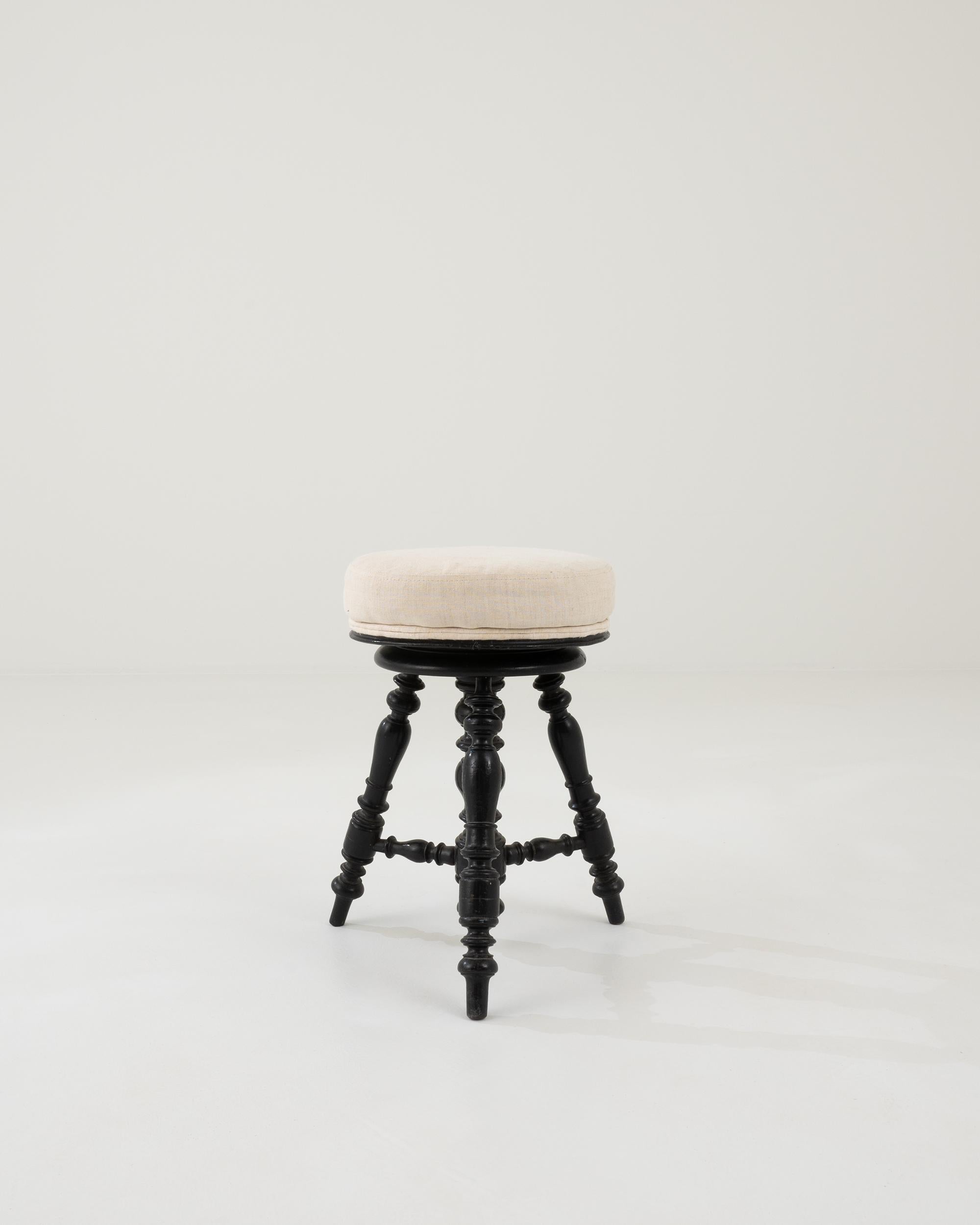 A minimal and decorative French design from circa 1900. Wooden turned legs support a round upholstered seat, rotating up and down with a spinning mechanism hidden inside a central column. Dramatic and reserved black with a great vintage patina,