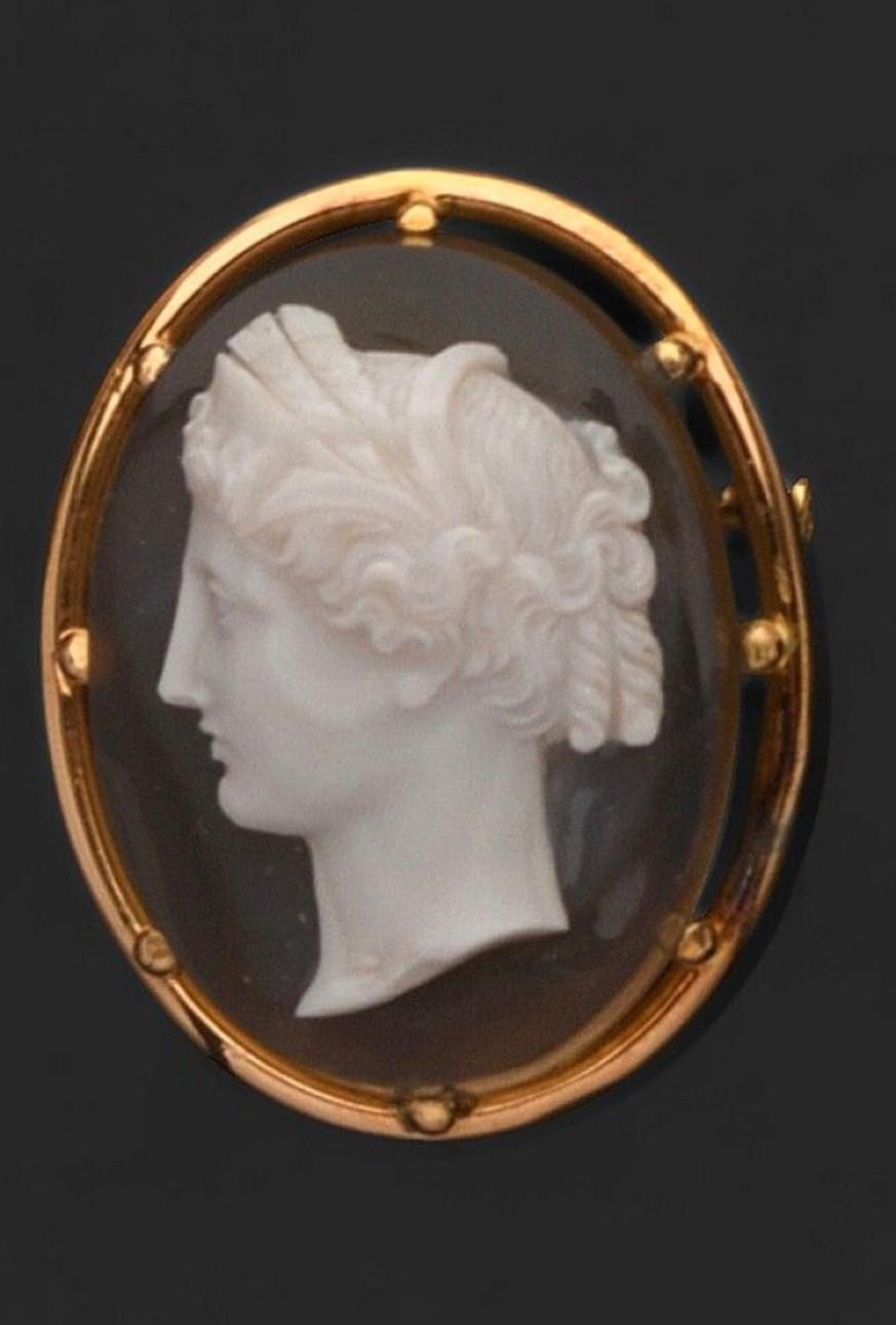 

CAMEO sur agate orné d'une jeune femme de profil tournée vers la gauche, les cheveux richement ciselés, monté sur or jaune 750 / °°, le métal en épingle. XIXème siècle. 3,7 x 4,5 cm. Poids brut : 23,5 g. 