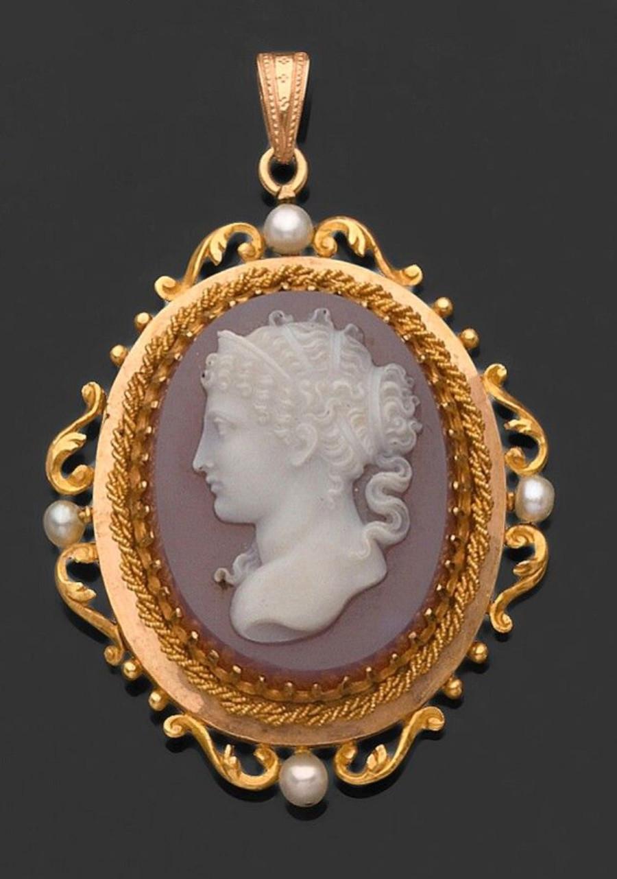 

PENDANT CAMEO, the setting in 750 / °° yellow gold braided and chiseled decorated with foliage punctuated with cultured pearls surrounding a woman in profile on agate, her hair richly chiseled and styled in the antique style. End of the 19th