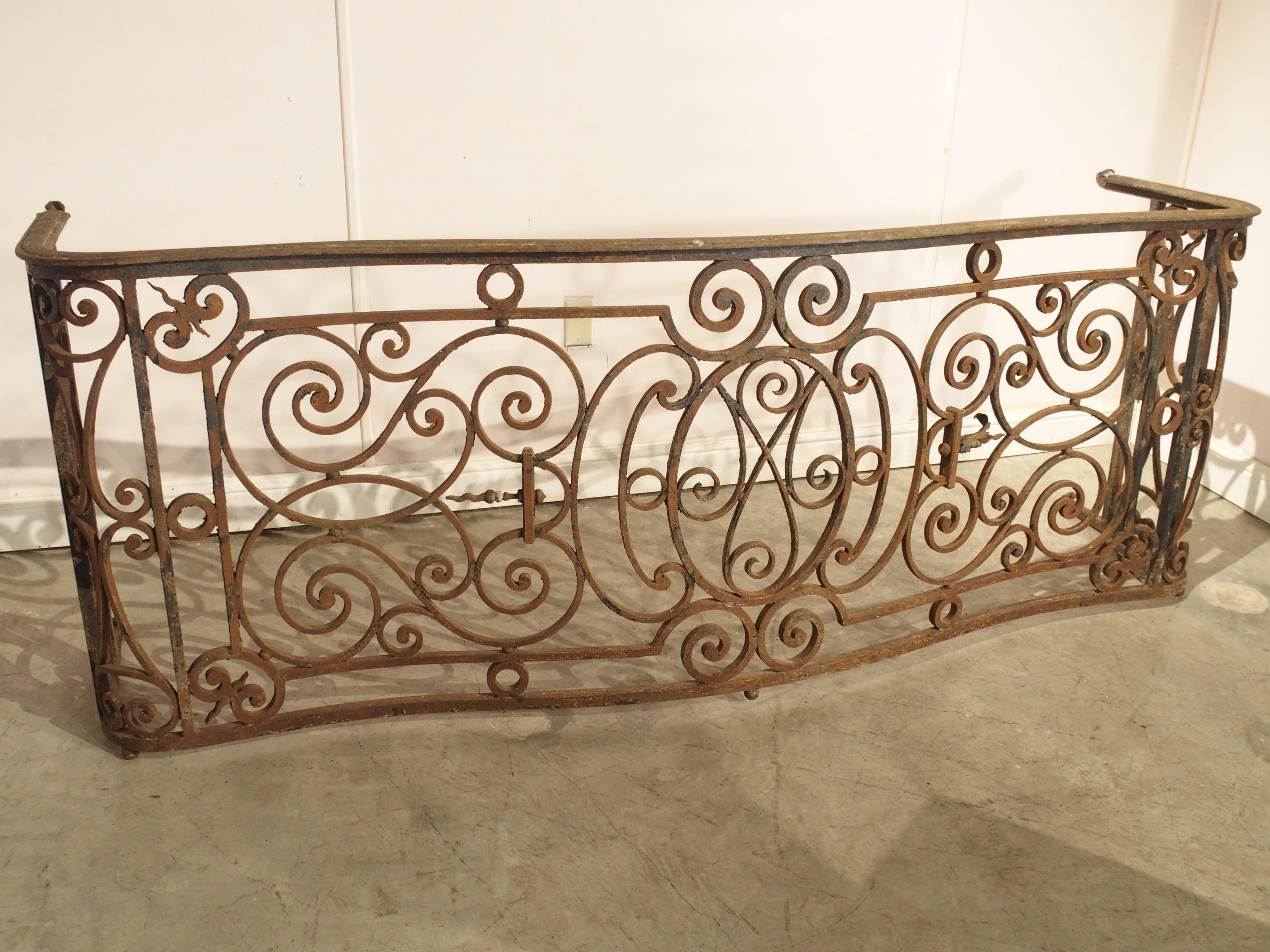 This beautiful French wrought iron balcony railing has been shaped in a form known as arbalete, or crossbow. The thick top rail has thin molding along the edges and features intact rear supports, which would have been anchored into the side of the
