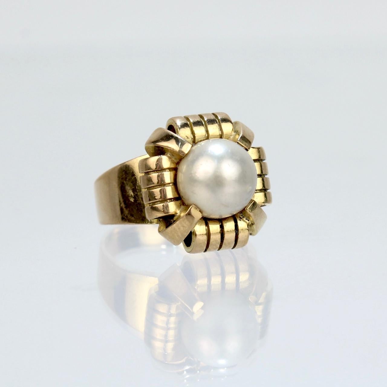 A fine French Art Deco period cocktail ring. 

In 18k yellow gold.

Prong set with a large ca. 9 mm off-round, slightly baroque white pearl in a shaped setting.

Hallmarked on the band with a French 'owl' import mark (that is partially