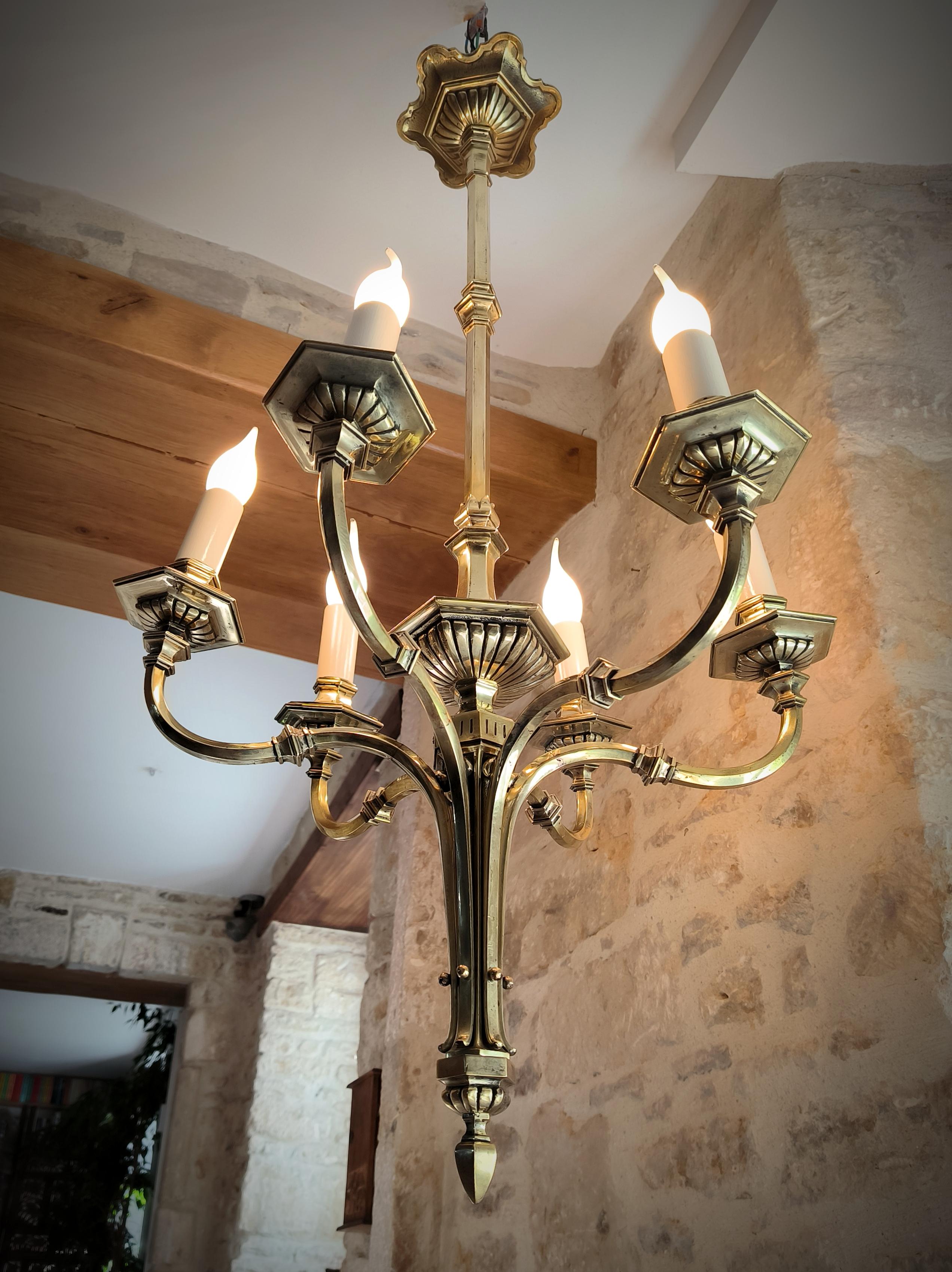 Proveniente dal dipartimento di Manche, in Normandia, Francia, questo magnifico lampadario in bronzo massiccio, quintessenza dell'arte French, ha un'atmosfera quasi gotica, grazie al suo peso meraviglioso e alla sua colonna centrale lunga 1 metro.