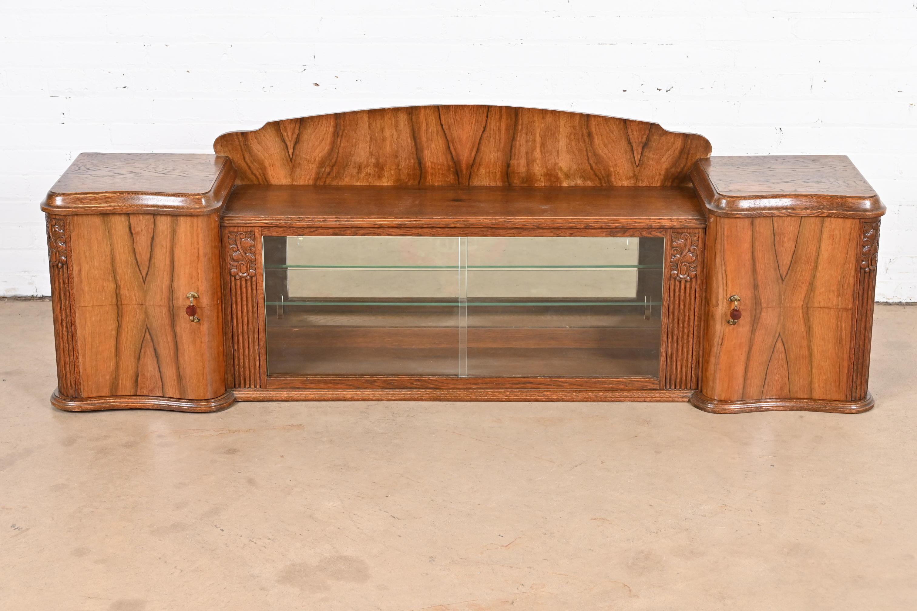 An outstanding French Art Deco table top display cabinet or bar cabinet

In the manner of Jules Leleu

France, circa 1930s

Carved oak, with gorgeous book-matched burled walnut front, original bakelite and brass hardware, sliding glass doors,