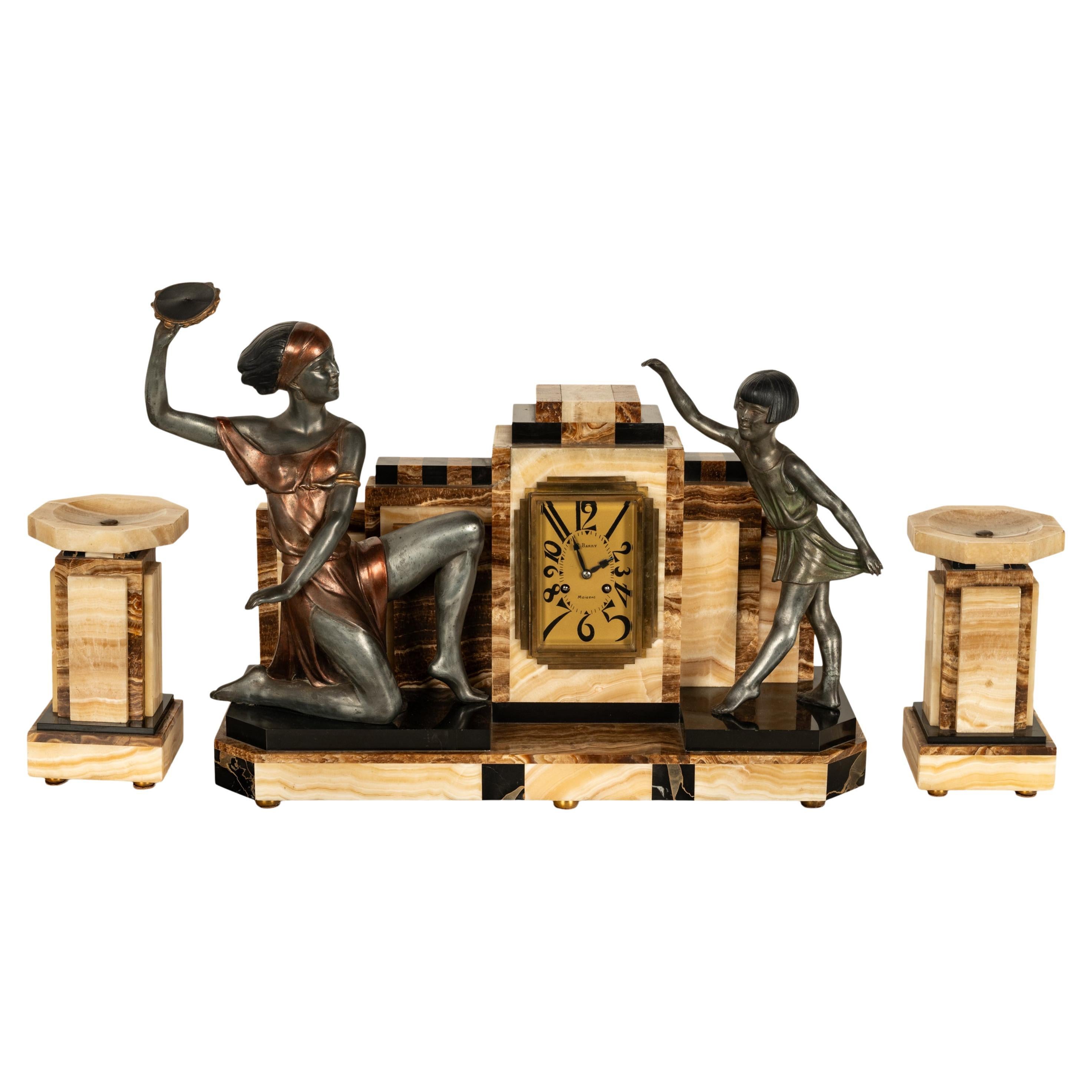 Antiguo reloj francés Art Decó de tres piezas de bronce y mármol pintado en frío, hacia 1925.
La guarnición consta de tres piezas, al centro el reloj de forma geométrica escalonada con cuatro colores de mármol abigarrado y está adornado con una