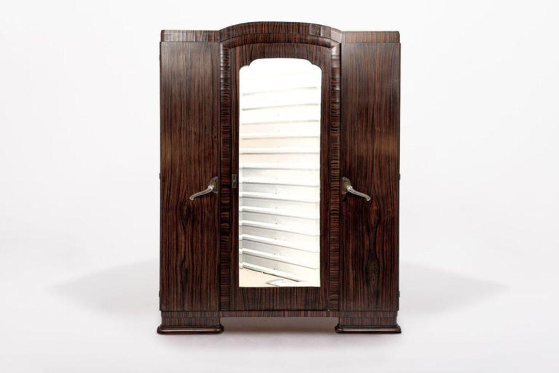 Este exquisito armario ropero antiguo de madera Art Decó se fabricó en Francia hacia 1940. Este armario alto está impecablemente hecho a mano con madera maciza y chapa de ébano de Macassar, con un asombroso veteado negro y marrón oscuro intenso. El