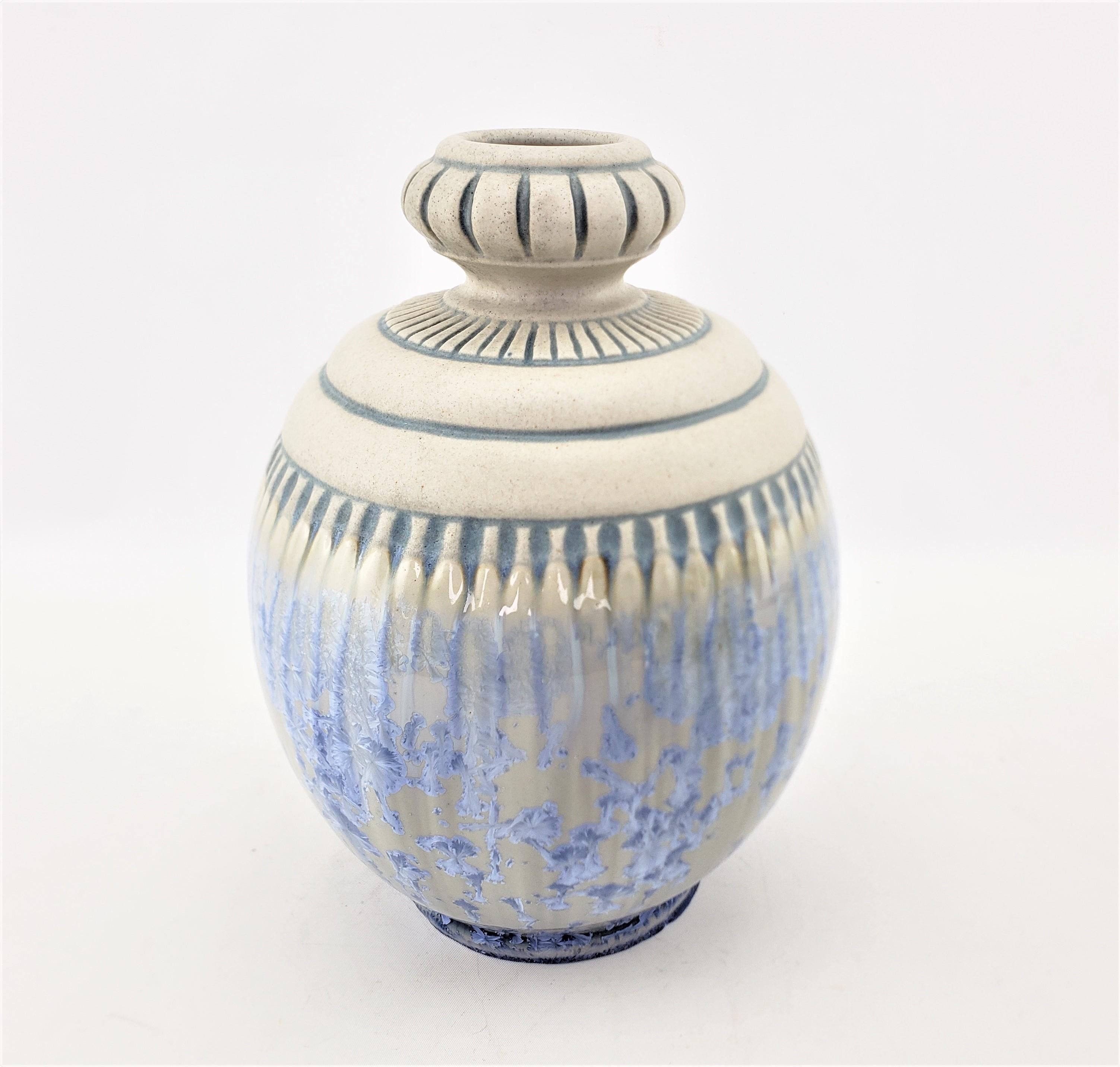 This art pottery vase was done by the renowned Mougin Nancy brothers of France in approximately 1920 in the period Art Deco style. The squat bulbous vase is done with a cream ground with blue accented indentations around the rim and center with a