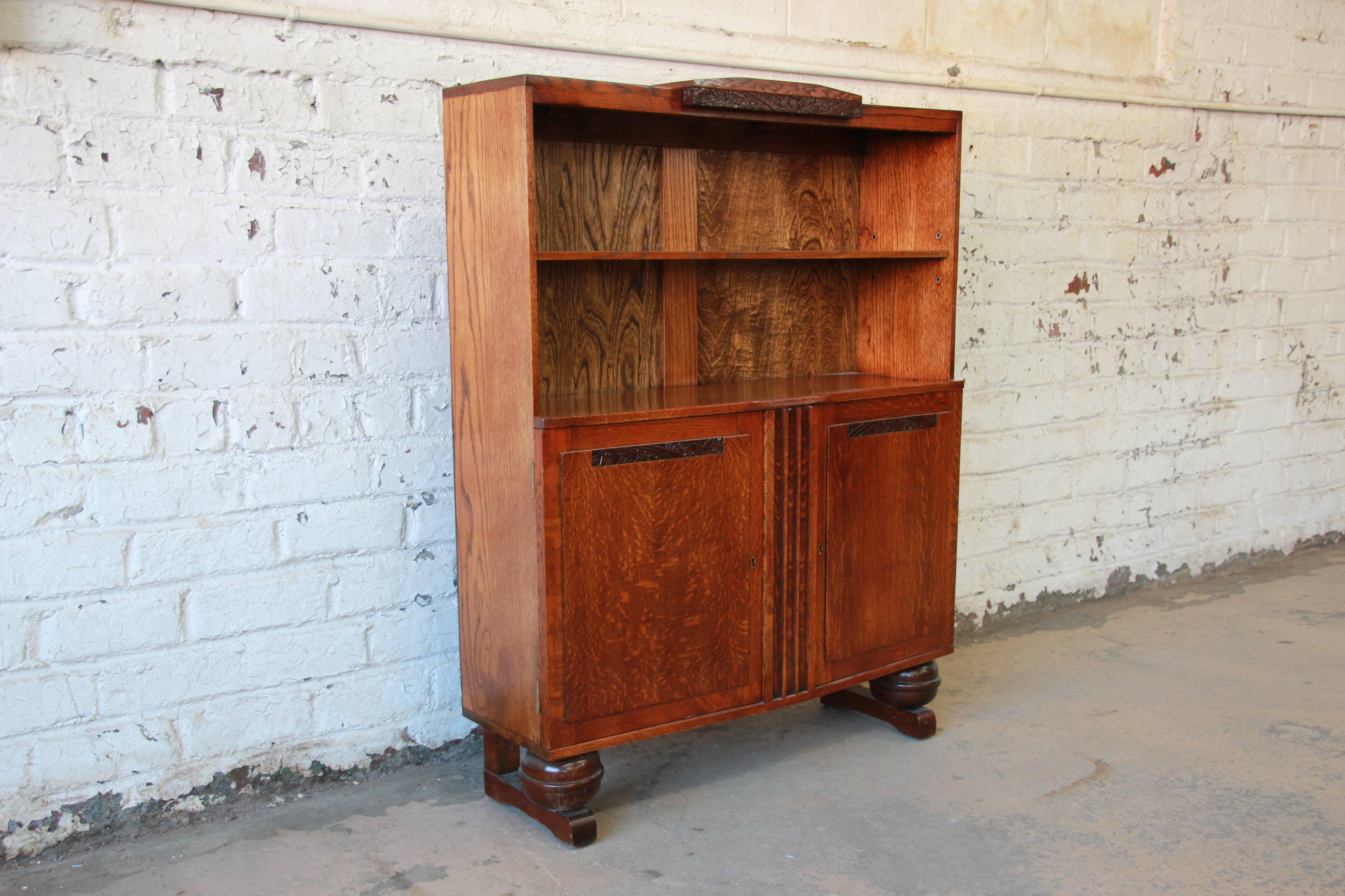 Offering a beautiful petite antique French Art Deco oak bookcase, circa 1920s. The top portion of the bookcase has an adjustable shelf with nice carved floral details above. The lower potion has two locking cabinet doors (locking key included) that